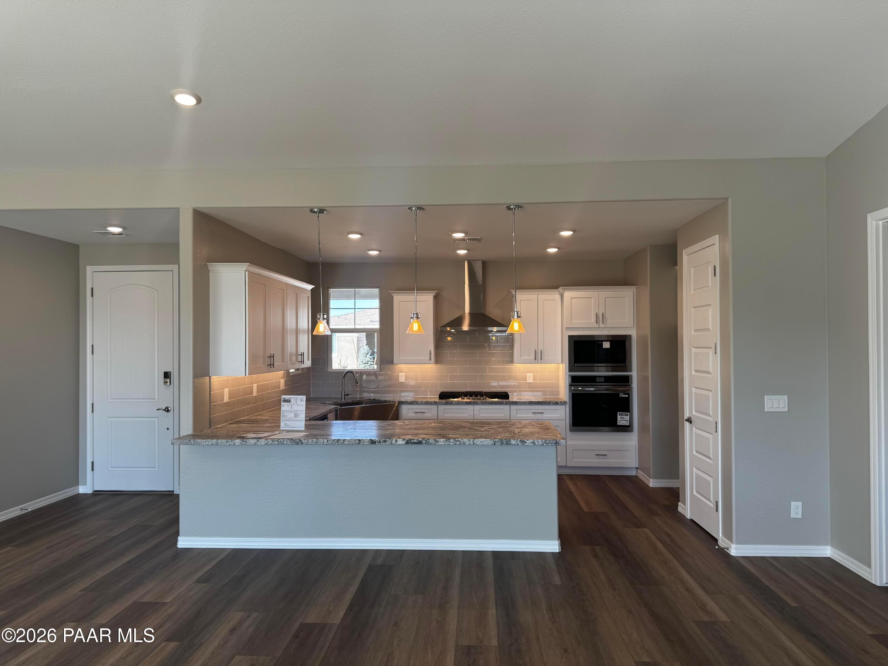 Modern open-concept kitchen with white cabinets, granite island, stainless appliances in Davidson Homes The Daybreak B, Prescott AZ