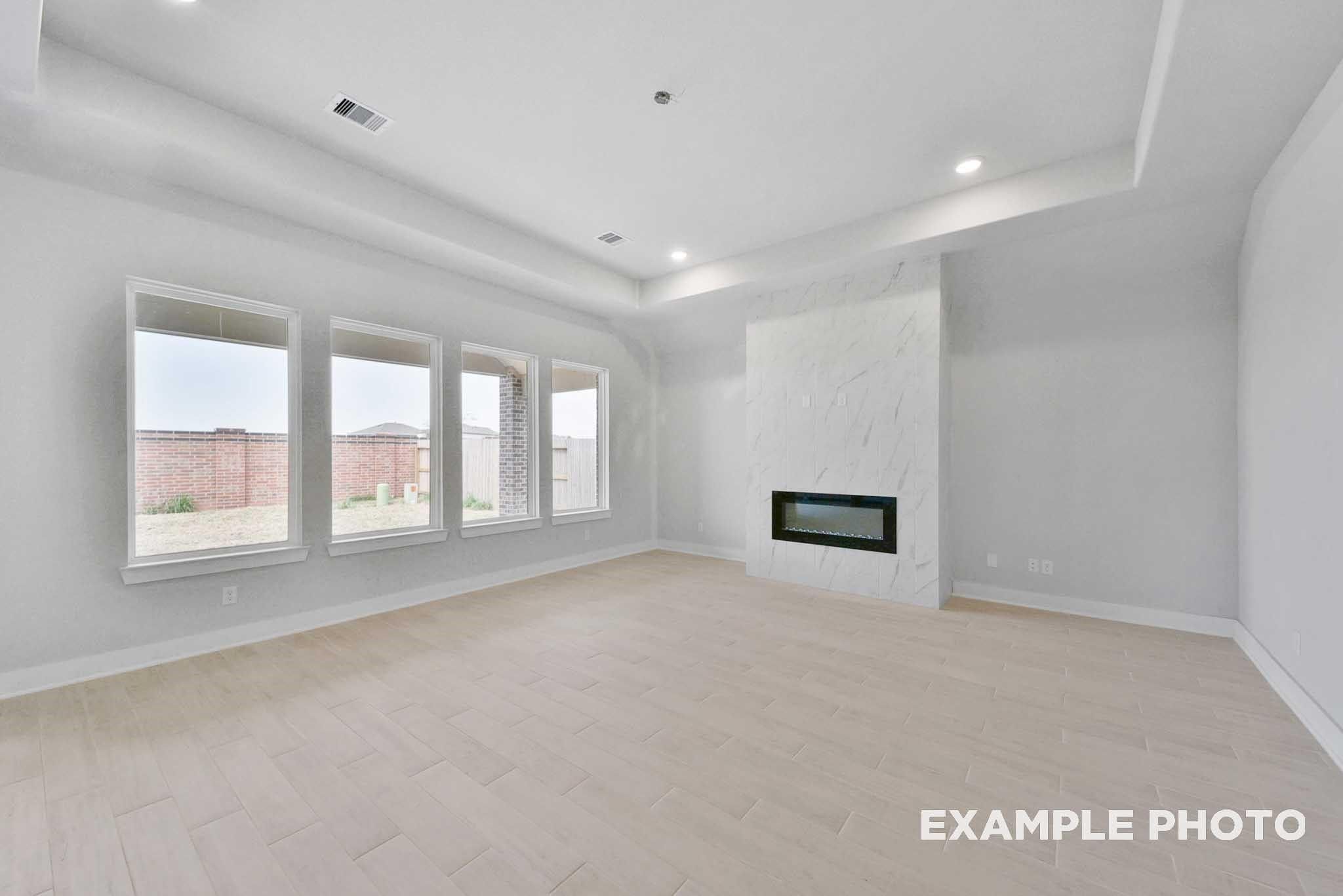 Spacious living room with modern white linear fireplace, light tile flooring, and large windows in Davidson Homes The George A, Texas City, Texas