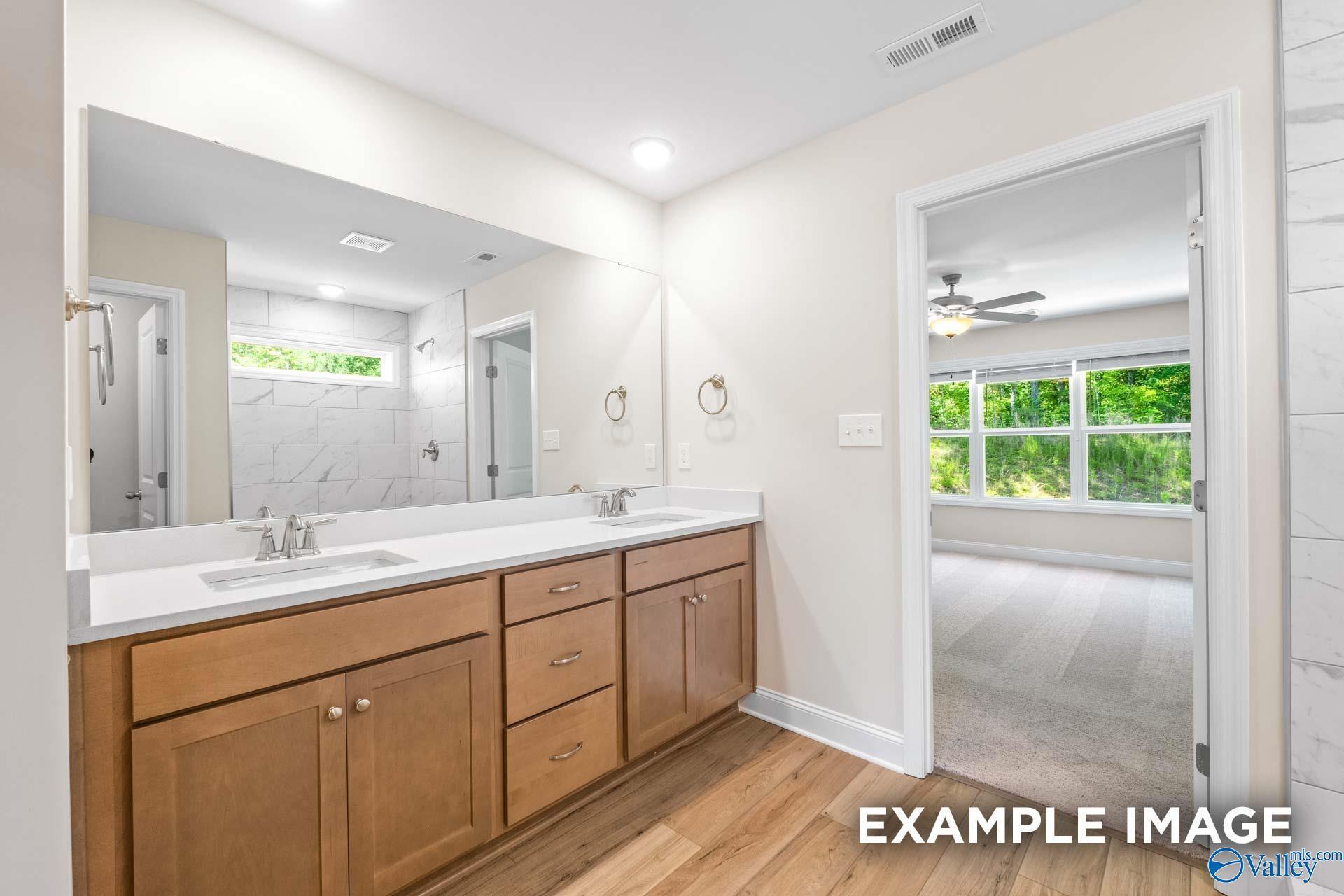 Modern master bathroom featuring double vanity, subway tile shower, and bedroom view in Davidson Homes The Shelby B, Arab, Alabama