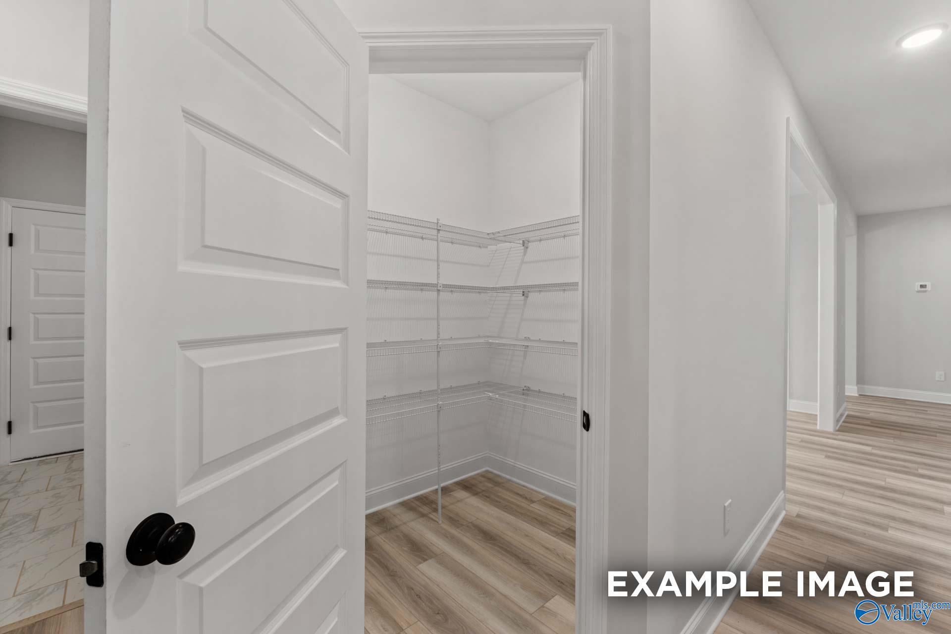 Spacious walk-in closet with open white doors, wire shelving, and hardwood floors in The Finleigh 3-bedroom home, Briercreek, Meridianville