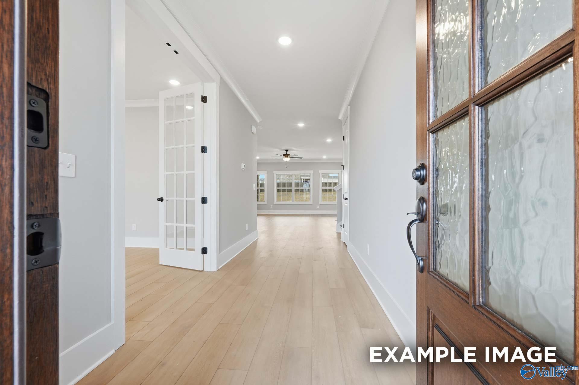 Elegant foyer with light oak floors, white walls, bifold doors, and frosted glass entry in Davidson Homes The Emory, Decatur AL