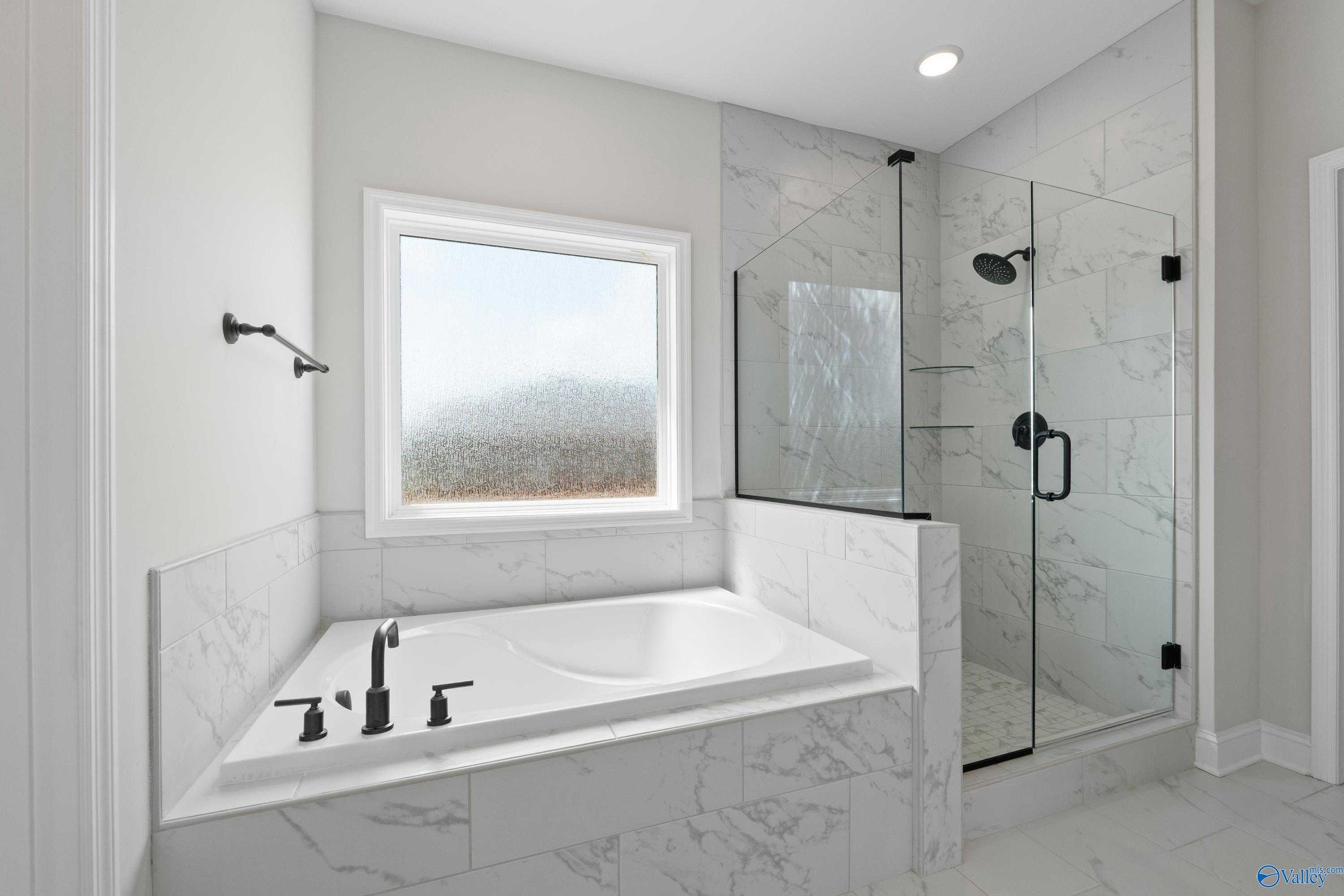 Luxurious master bath with freestanding soaking tub, glass shower, and frosted window in Davidson Homes The Rockford, Toney, AL