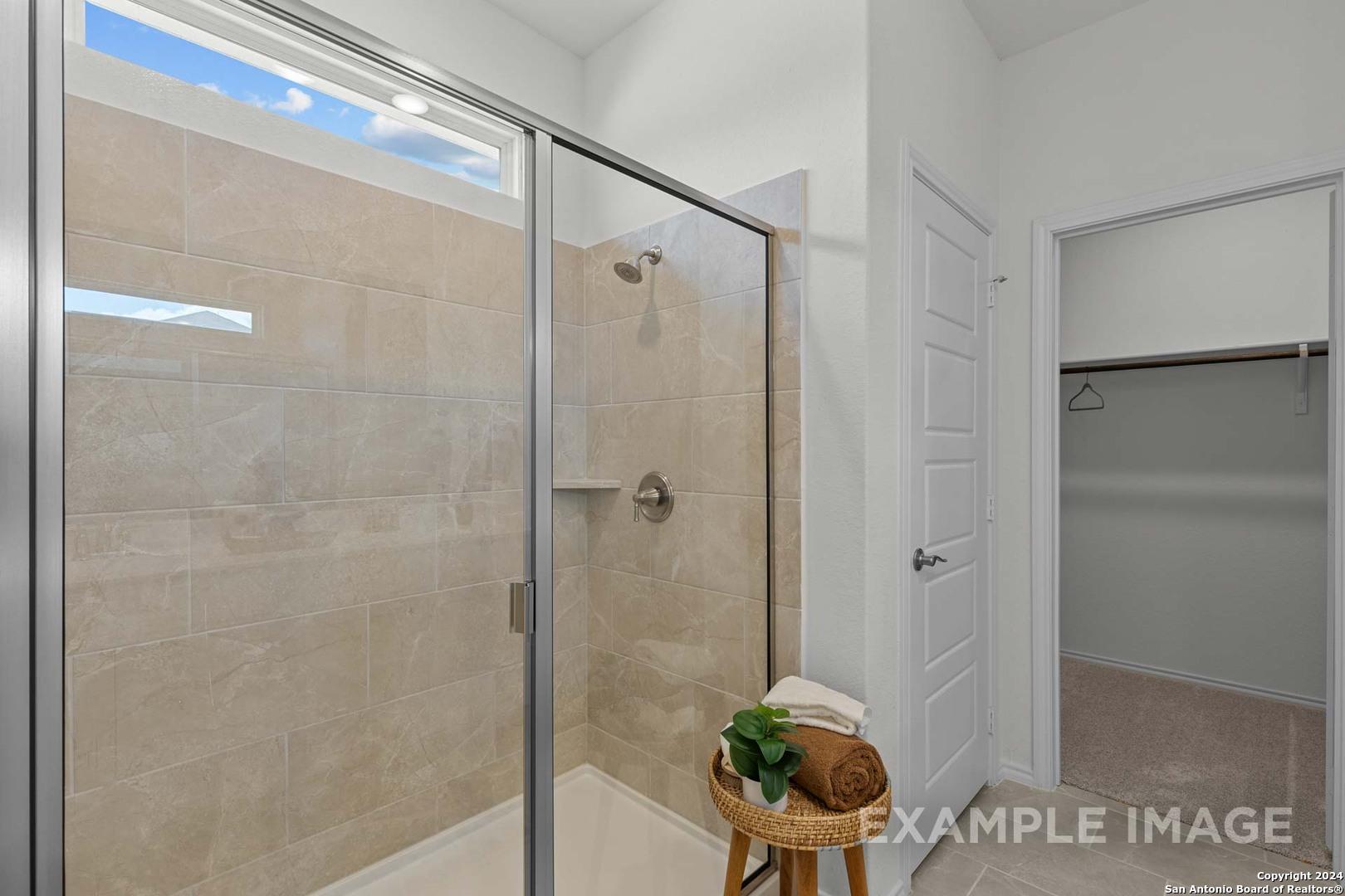 Modern walk-in shower with frameless glass door and neutral tile in master bath, The Daphne K by Davidson Homes, San Antonio