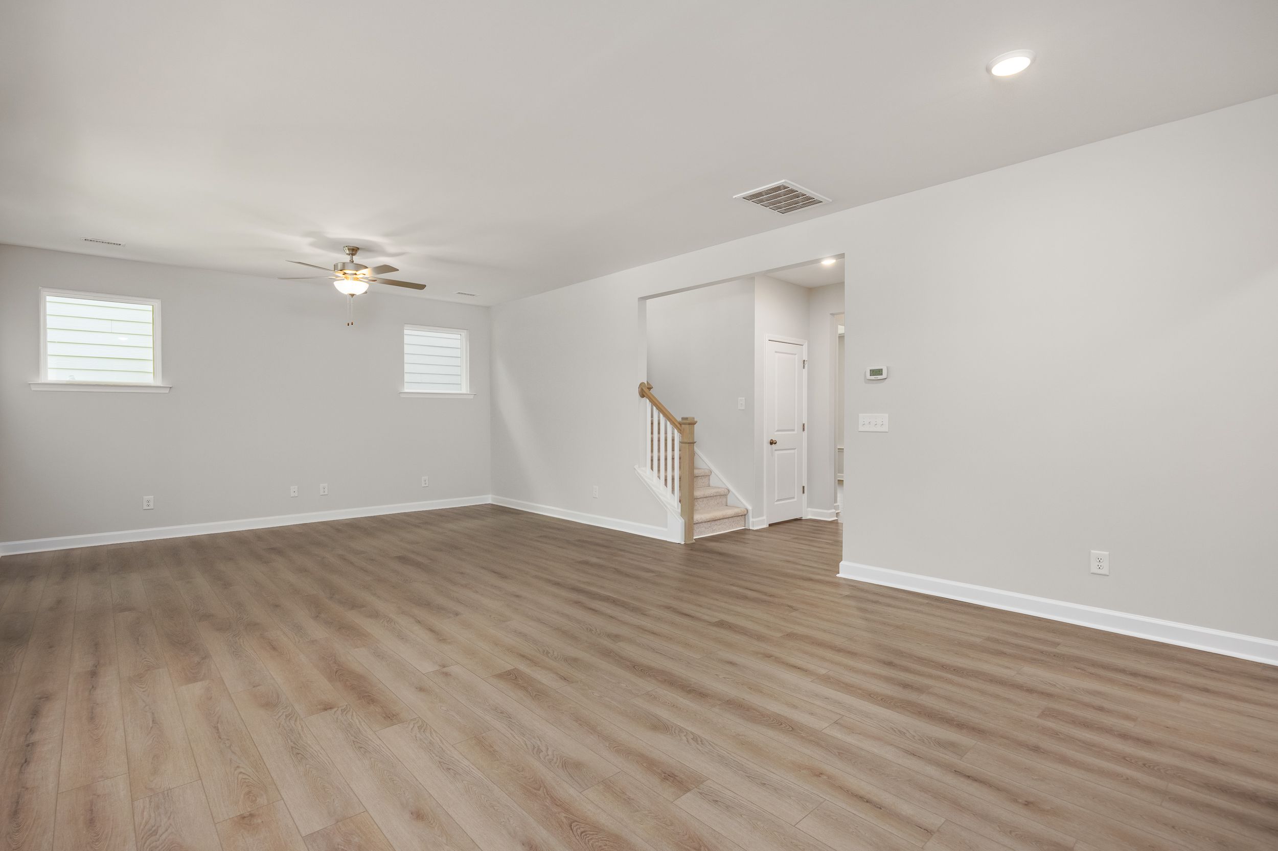 Spacious open foyer in The Aspen C two-story home with wooden staircase, light hardwood floors, and ceiling fan