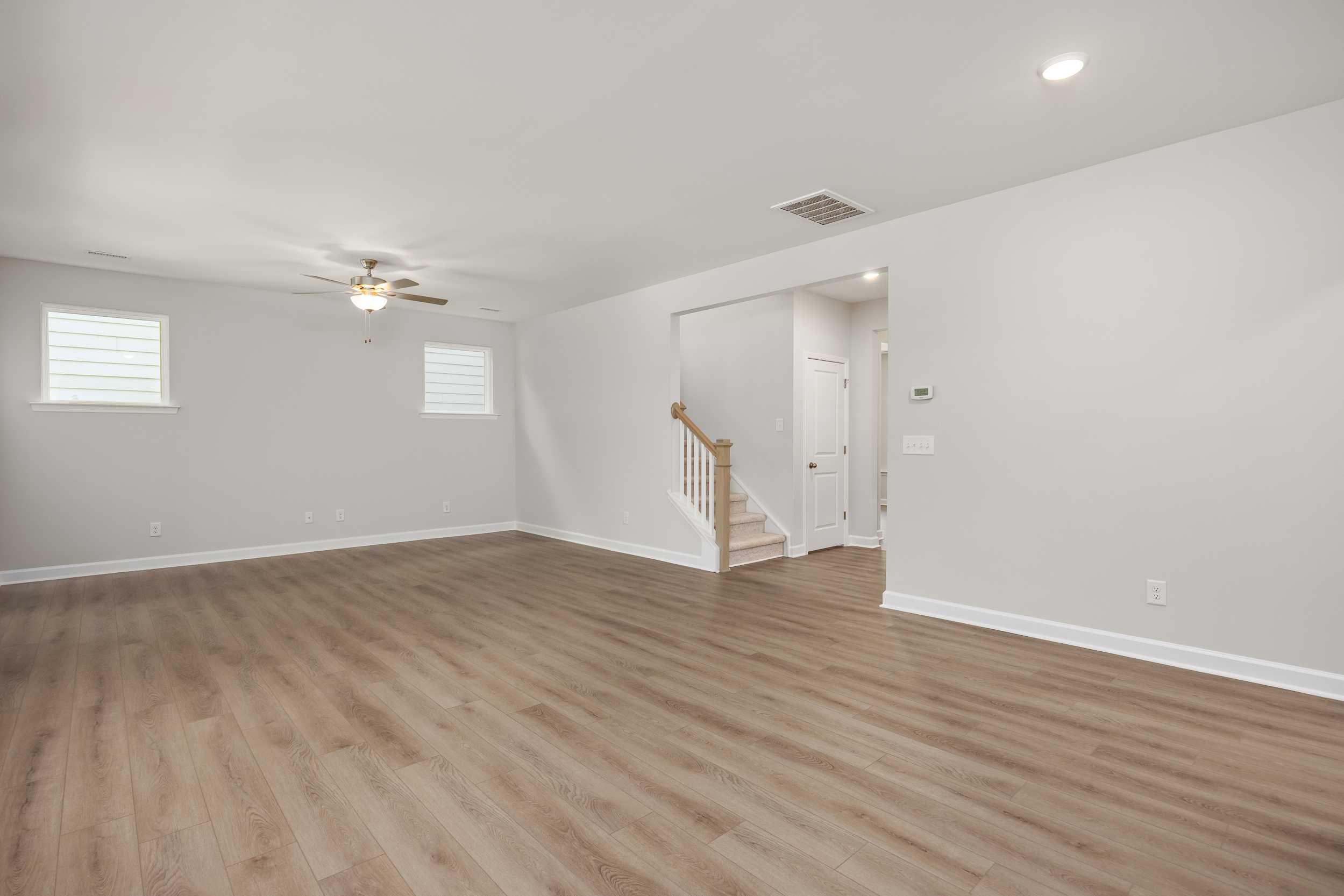 Spacious open foyer in The Aspen C two-story home with wooden staircase, light hardwood floors, and ceiling fan