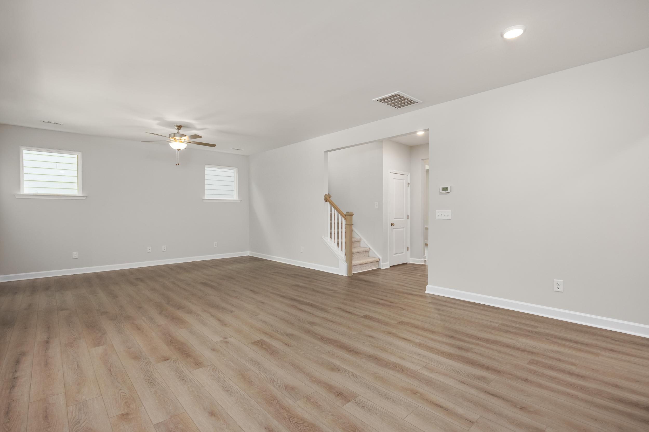 Spacious open foyer in The Aspen C two-story home with wooden staircase, light hardwood floors, and ceiling fan