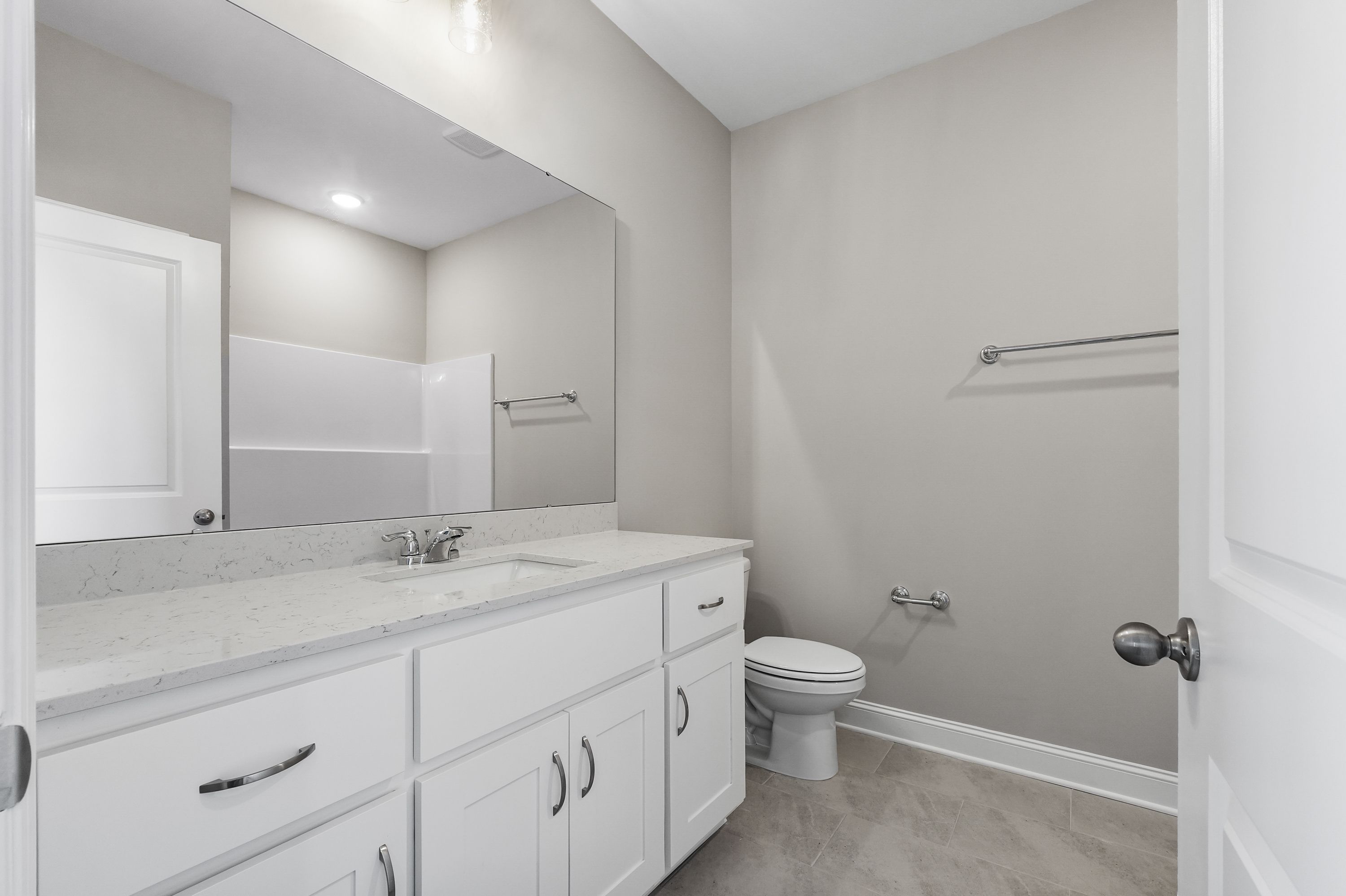 Spacious master bathroom in The Valencia featuring double white vanity, quartz countertop, large mirror, and neutral tones