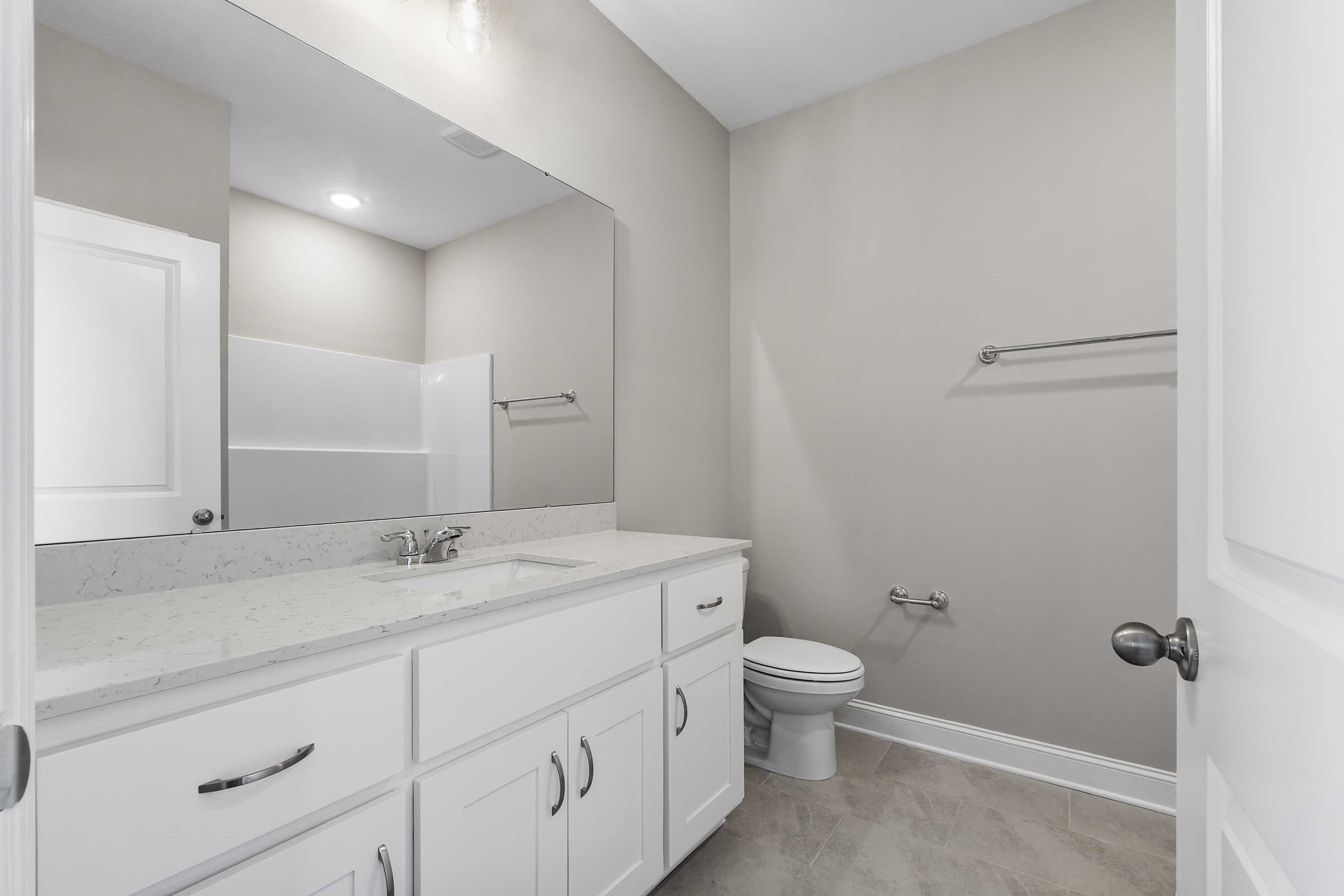 Spacious master bathroom in The Valencia featuring double white vanity, quartz countertop, large mirror, and neutral tones