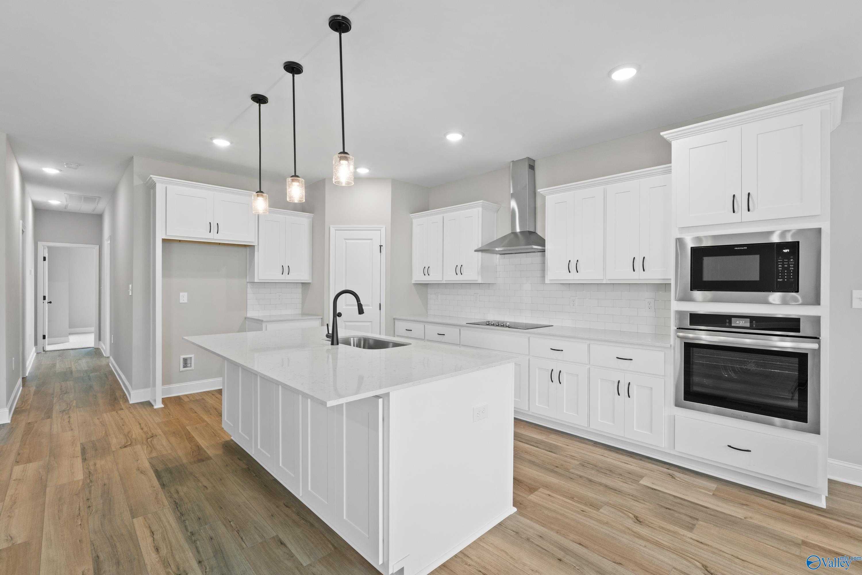 Bright modern kitchen with white shaker cabinets, quartz island sink, stainless double oven in Davidson Homes The Rockford, Toney AL