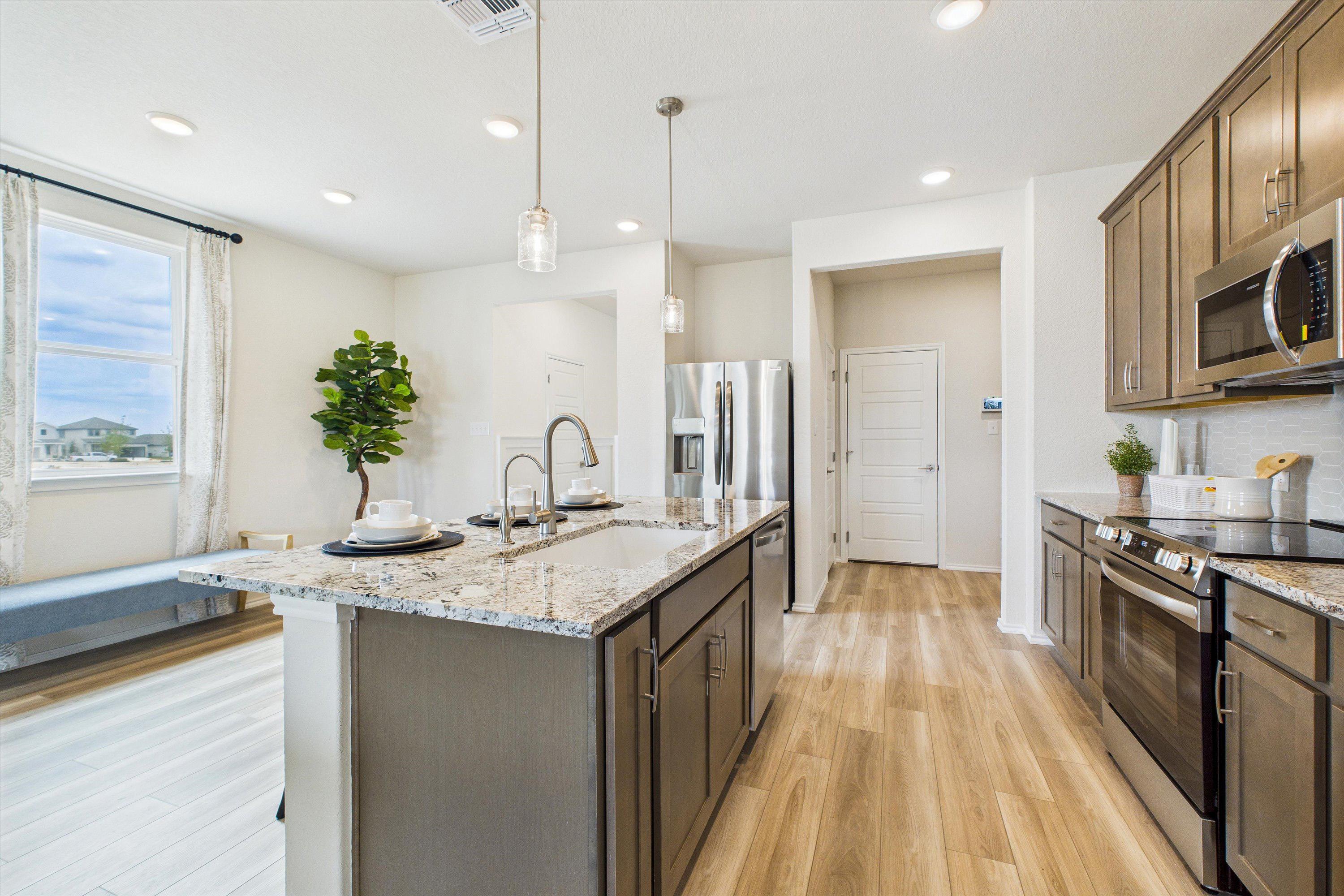 Spacious modern kitchen at Fairway Crossing in Converse TX with granite island, stainless appliances, hardwood floors