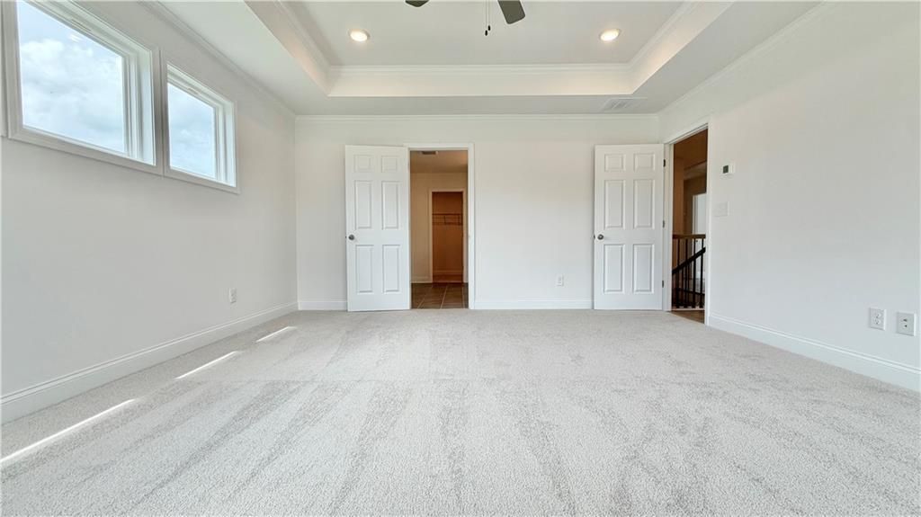 Spacious bedroom with tray ceiling and walk-in closet in The Hickory C floor plan by Davidson Homes in Hoschton, Georgia.