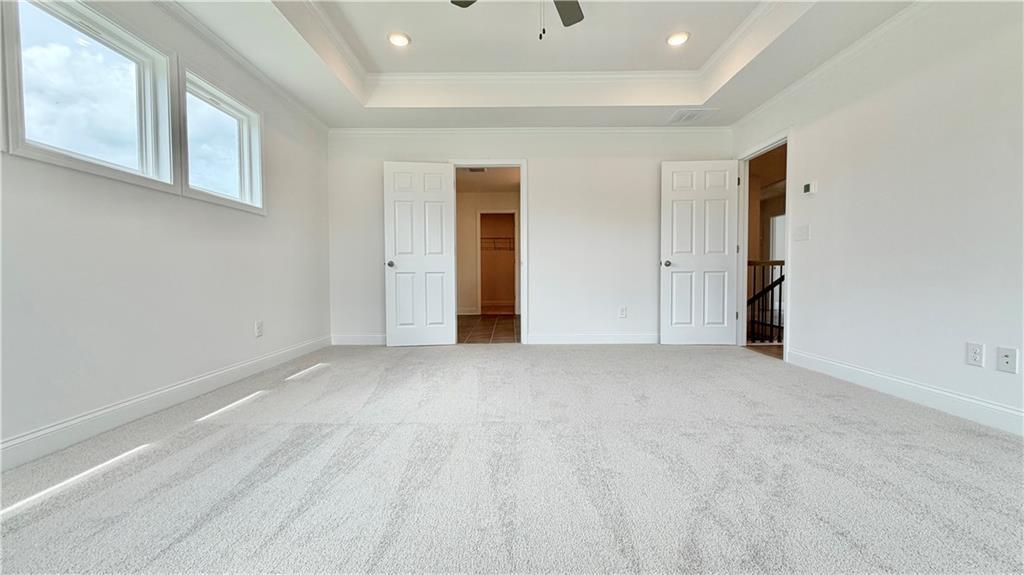 Spacious bedroom with tray ceiling and walk-in closet in The Hickory C floor plan by Davidson Homes in Hoschton, Georgia.
