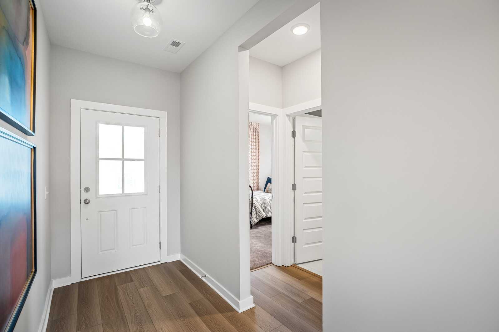 Bright entry hallway at Sage Farms in White House TN with light hardwood floors, white paneled doors, and abstract wall art