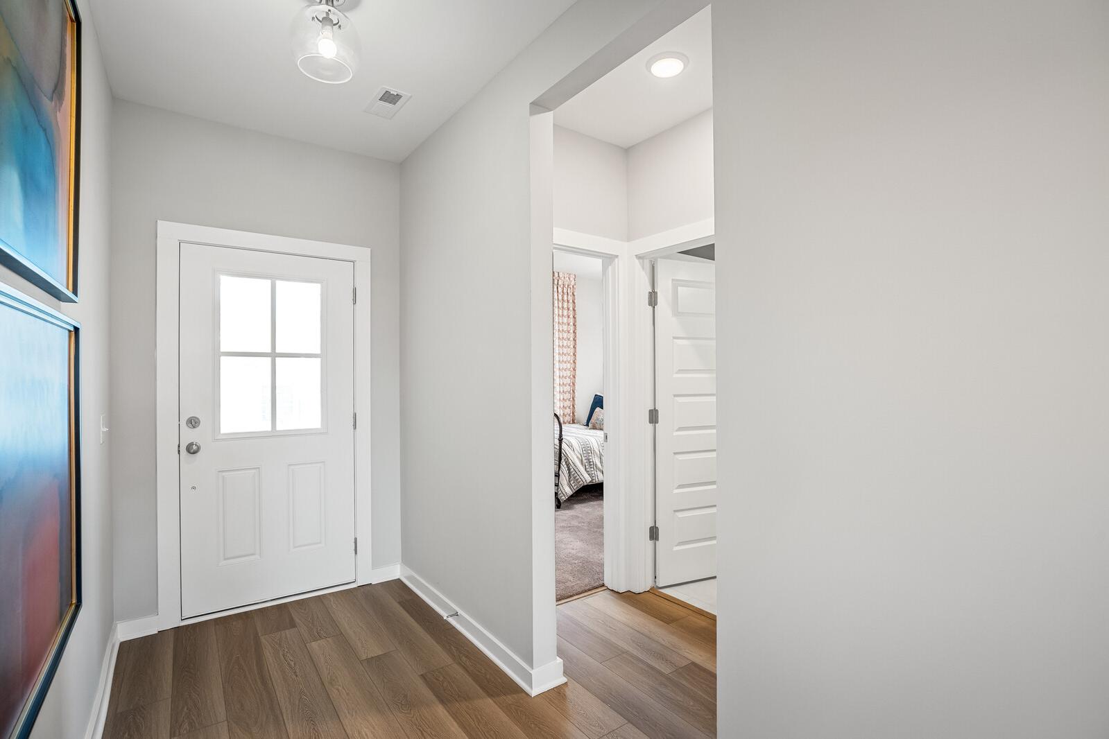 Bright entry hallway at Sage Farms in White House TN with light hardwood floors, white paneled doors, and abstract wall art