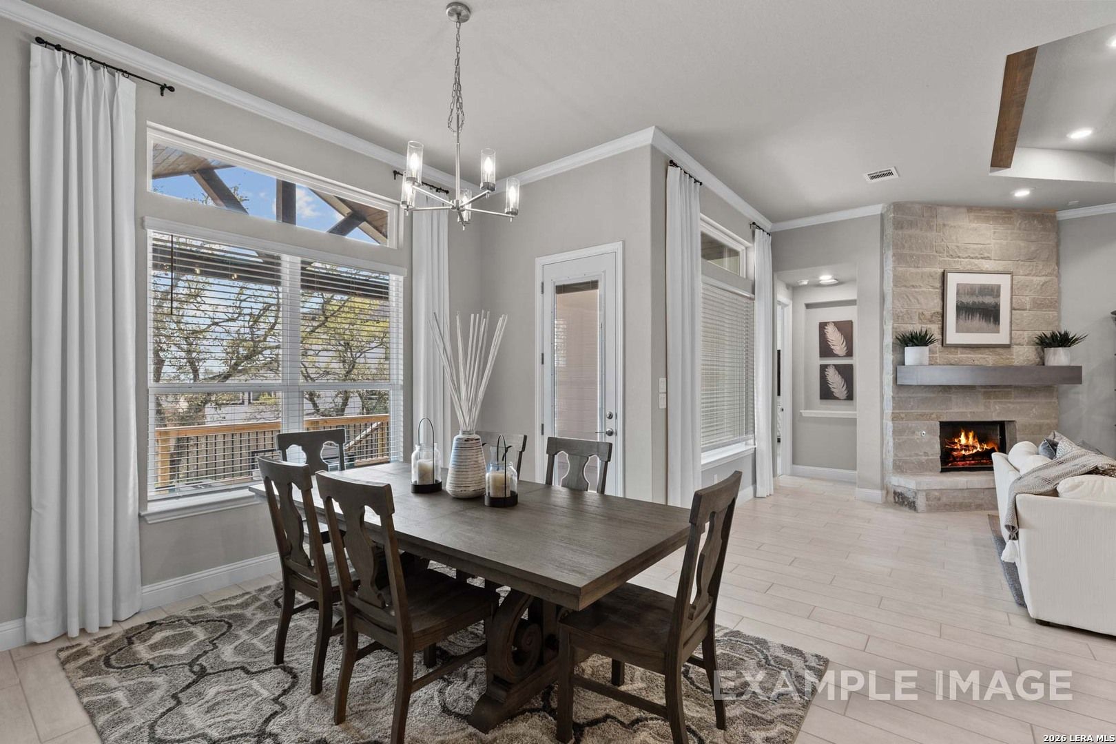 Dining area with wood table and stone fireplace in The Garner C floor plan at The Reserve at Potranco Oaks, Castroville.