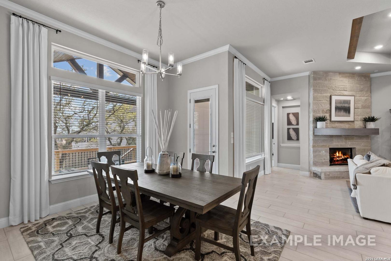Dining area with wood table and stone fireplace in The Garner C floor plan at The Reserve at Potranco Oaks, Castroville.