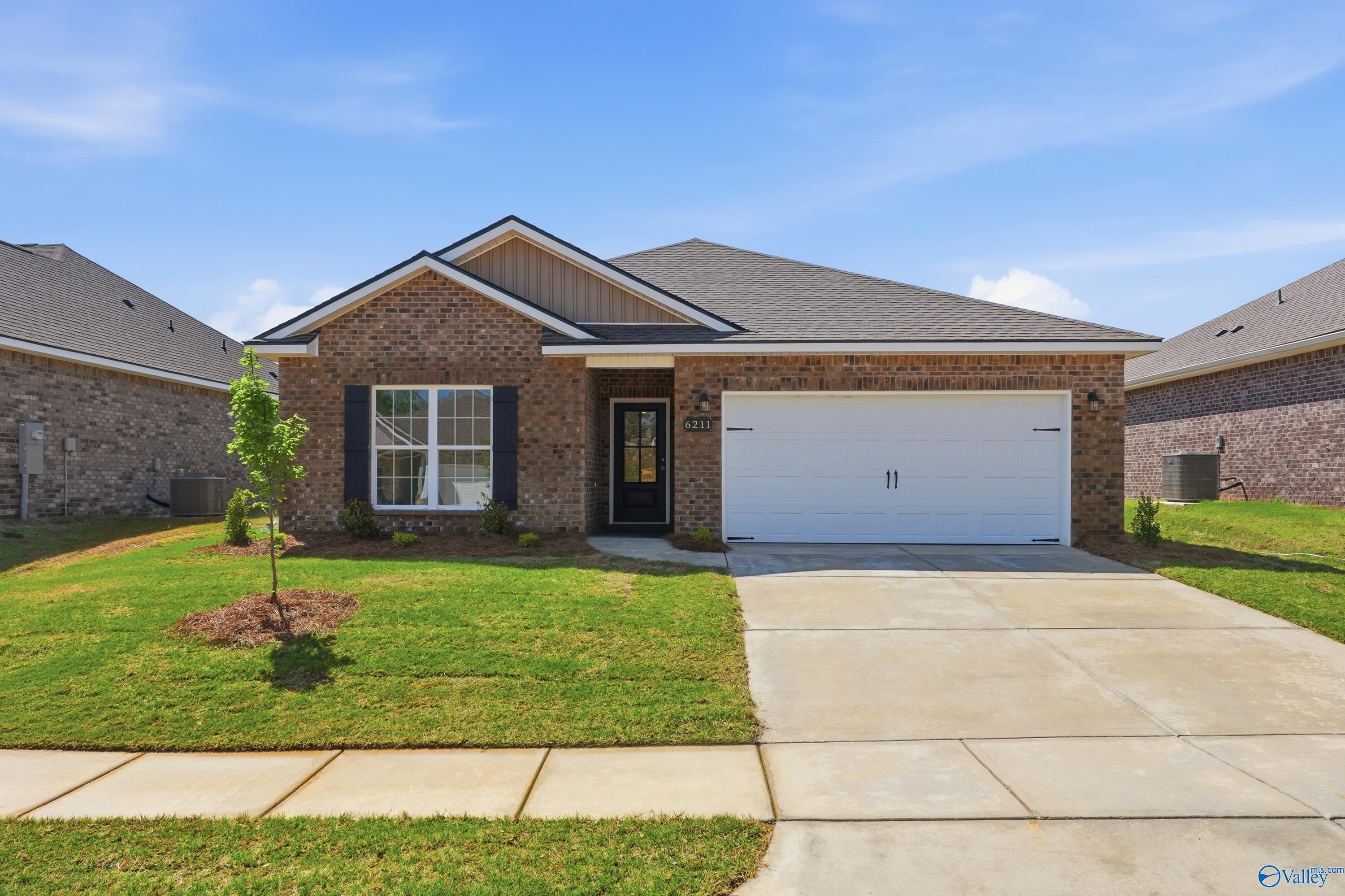 Brick single-story home with 2-car garage, black front door, and landscaped front yard in Jaguar Hills, Huntsville, Alabama - Davidson Homes Asheville