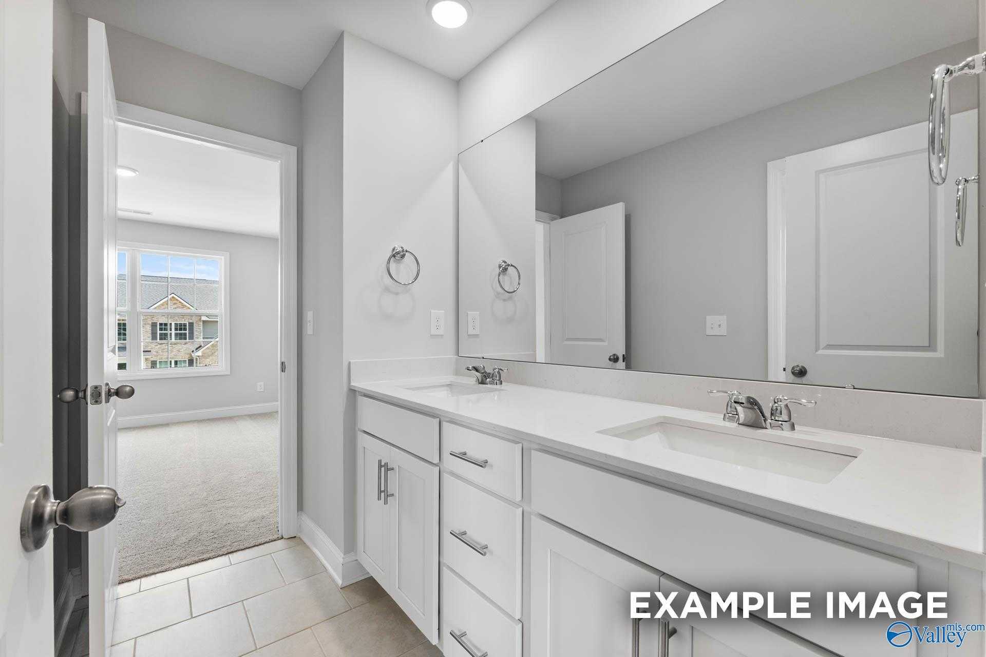 Bright guest bathroom with white shaker vanity, single sink, large mirror, and neutral gray walls in Davidson Homes The Madison A, Harvest AL