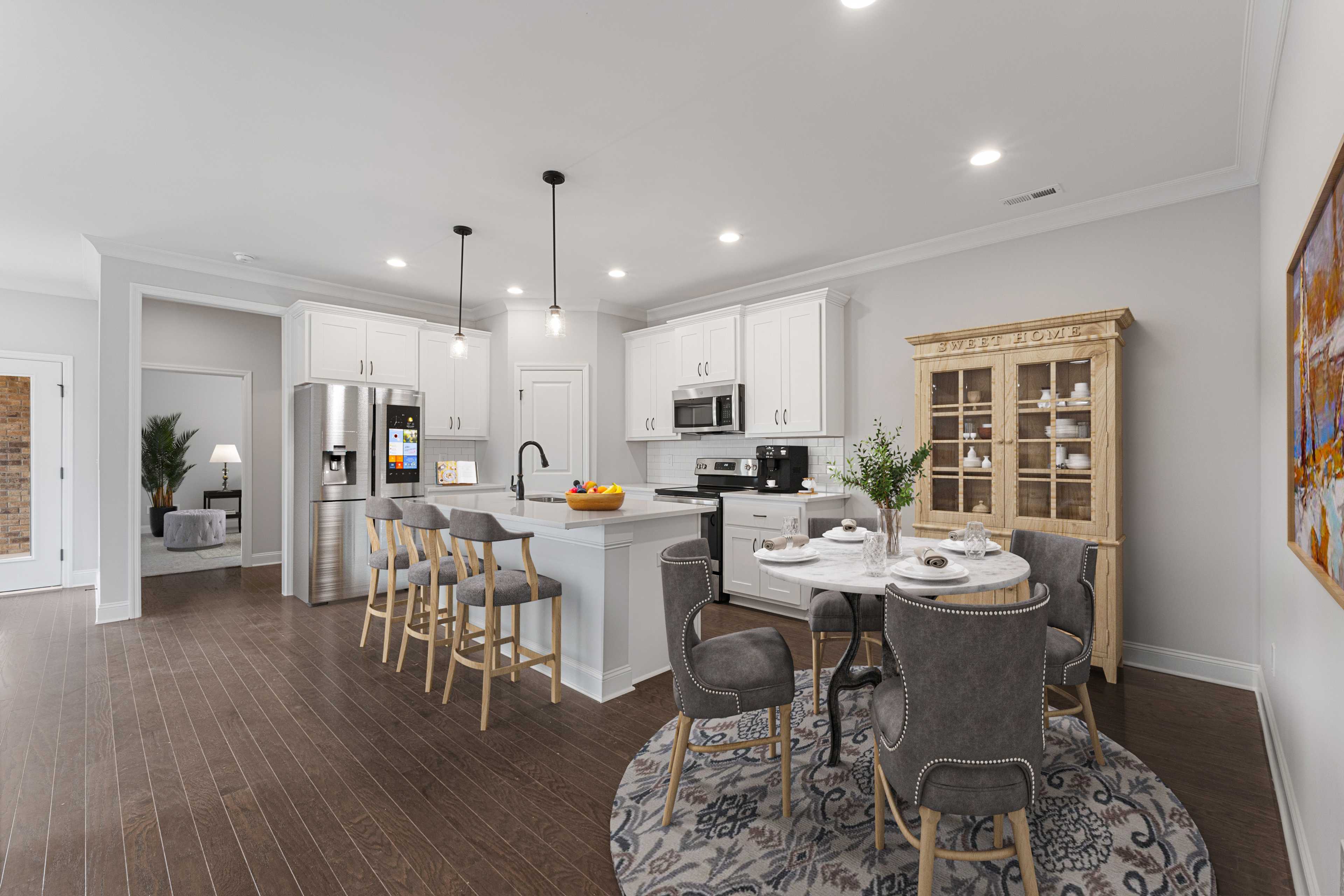 Modern open-concept kitchen and dining at The Villas at Barnett's Crossing in Madison, AL with white cabinets, gray island, hardwood floors