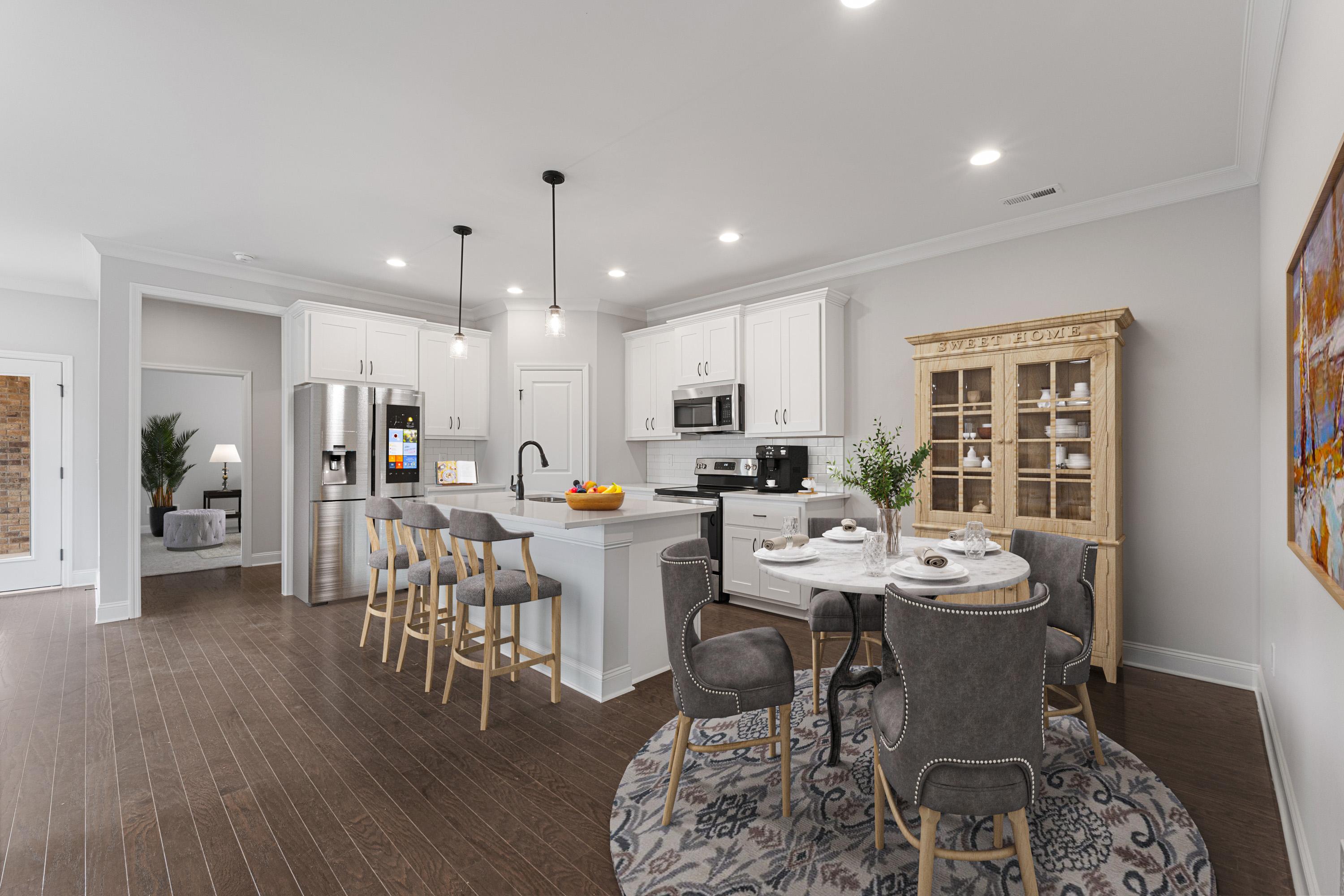 Modern open-concept kitchen and dining at The Villas at Barnett's Crossing in Madison, AL with white cabinets, gray island, hardwood floors
