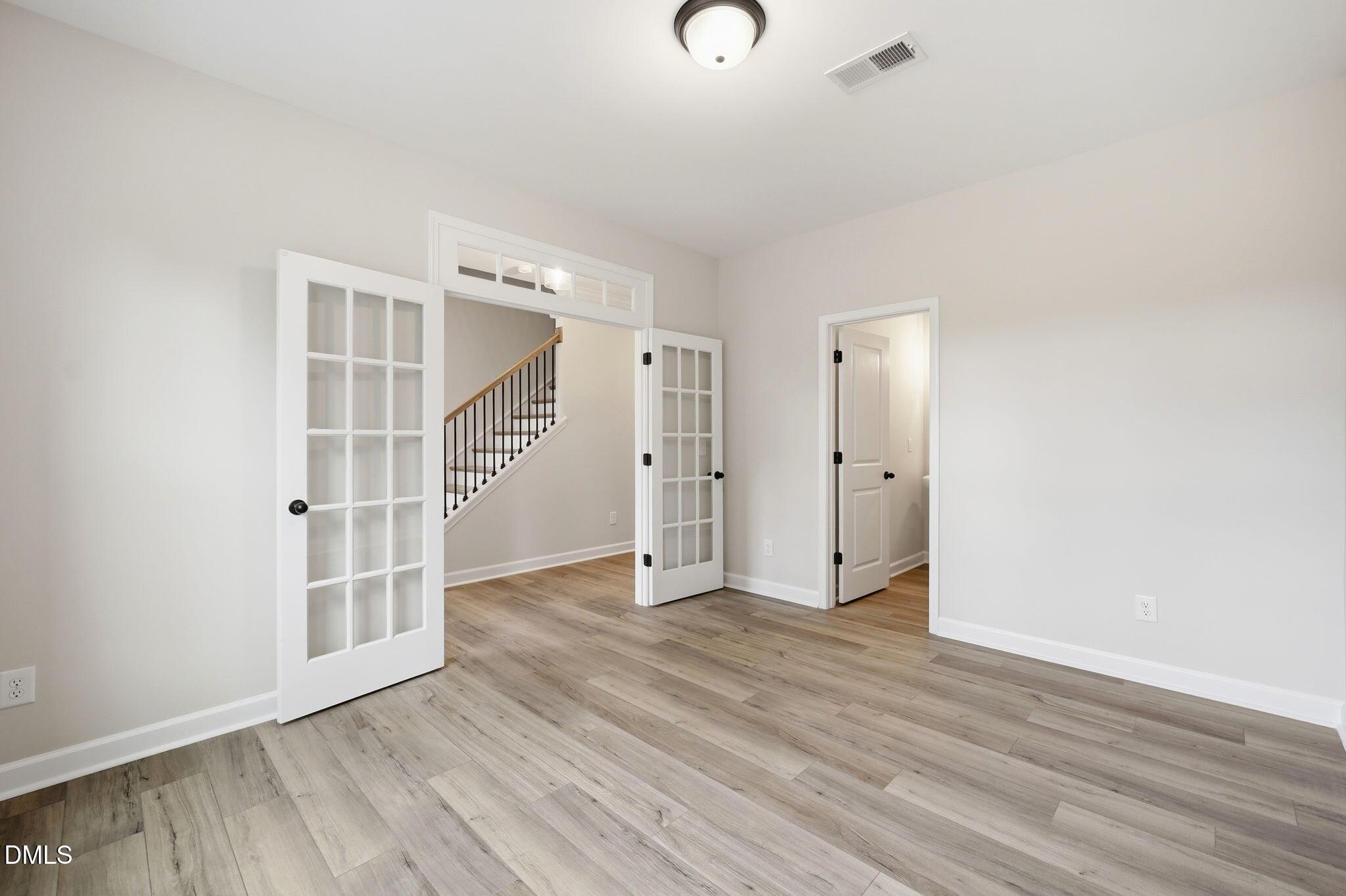 Bright flex room with French doors and wood-look flooring in The Mitchell Interior floor plan, Camden Park, Knightdale, NC.