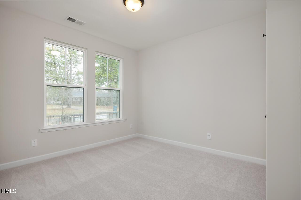 Bright secondary bedroom with beige carpet, gray walls, and large windows overlooking trees in The Mitchell Interior, Knightdale NC