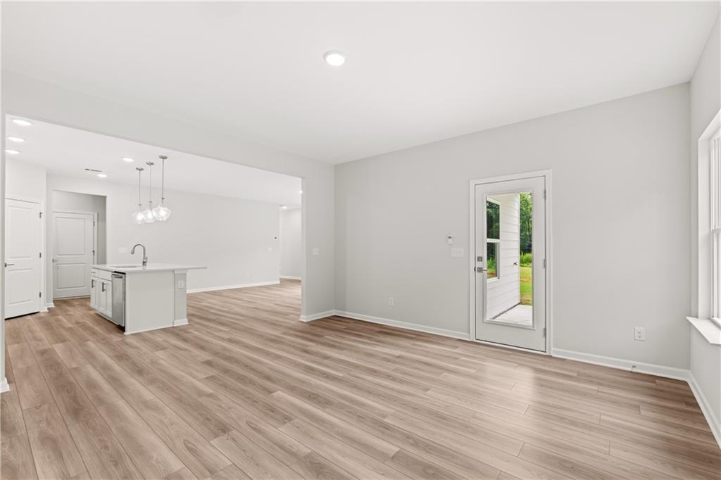 Bright open-concept living area with wood-style flooring and backyard access in The Russell A floor plan at Cedar Farms.