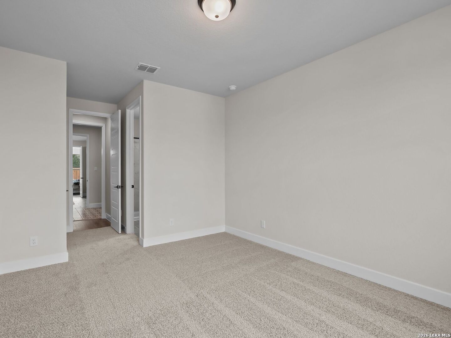 Spacious carpeted bedroom with neutral walls in The Belmont H floor plan at Potranco Oaks, Castroville, Texas.