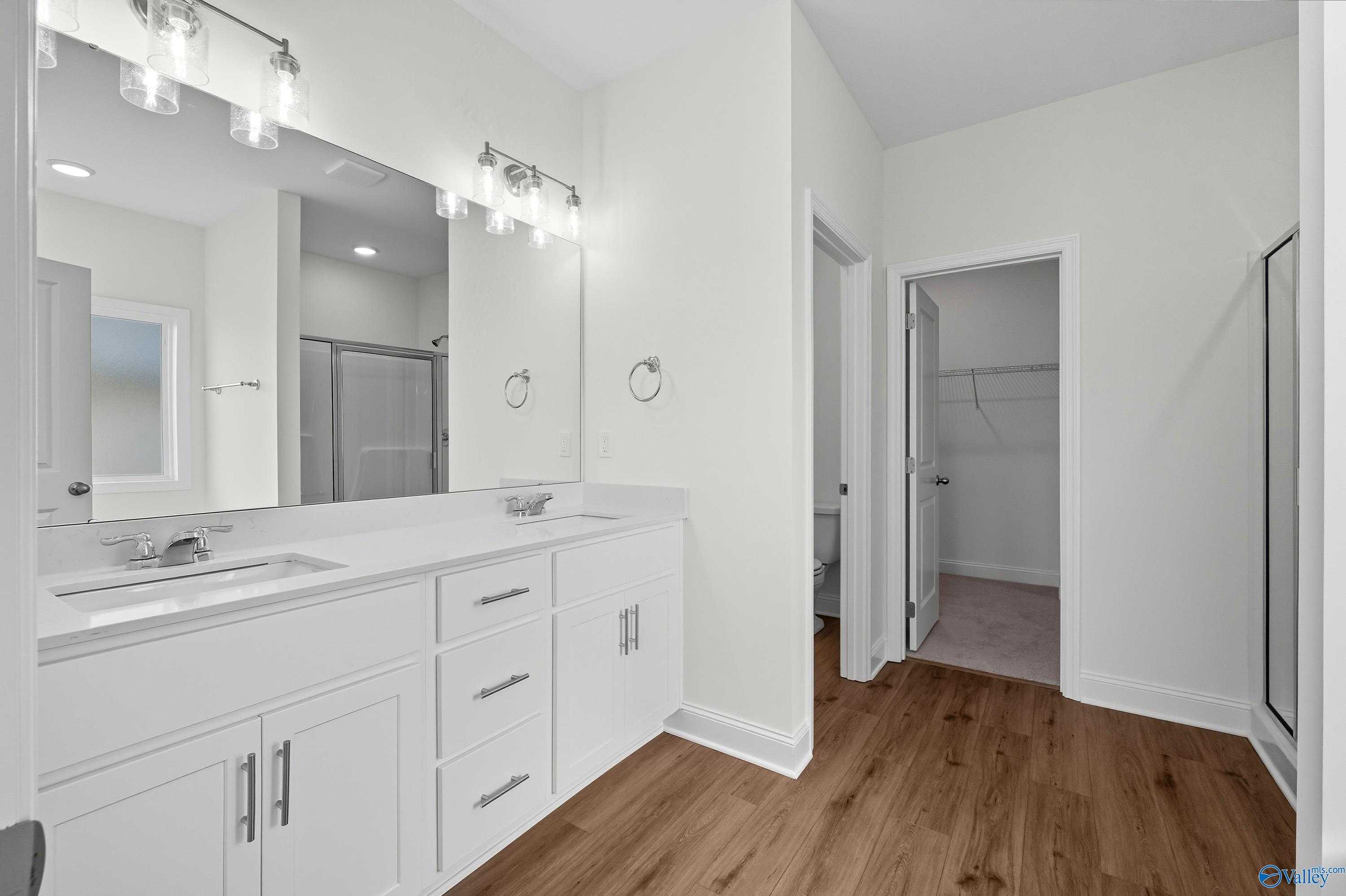 Modern master bathroom with double vanity, frameless glass shower, walk-in closet in Davidson Homes The Everett, Meridianville, Alabama