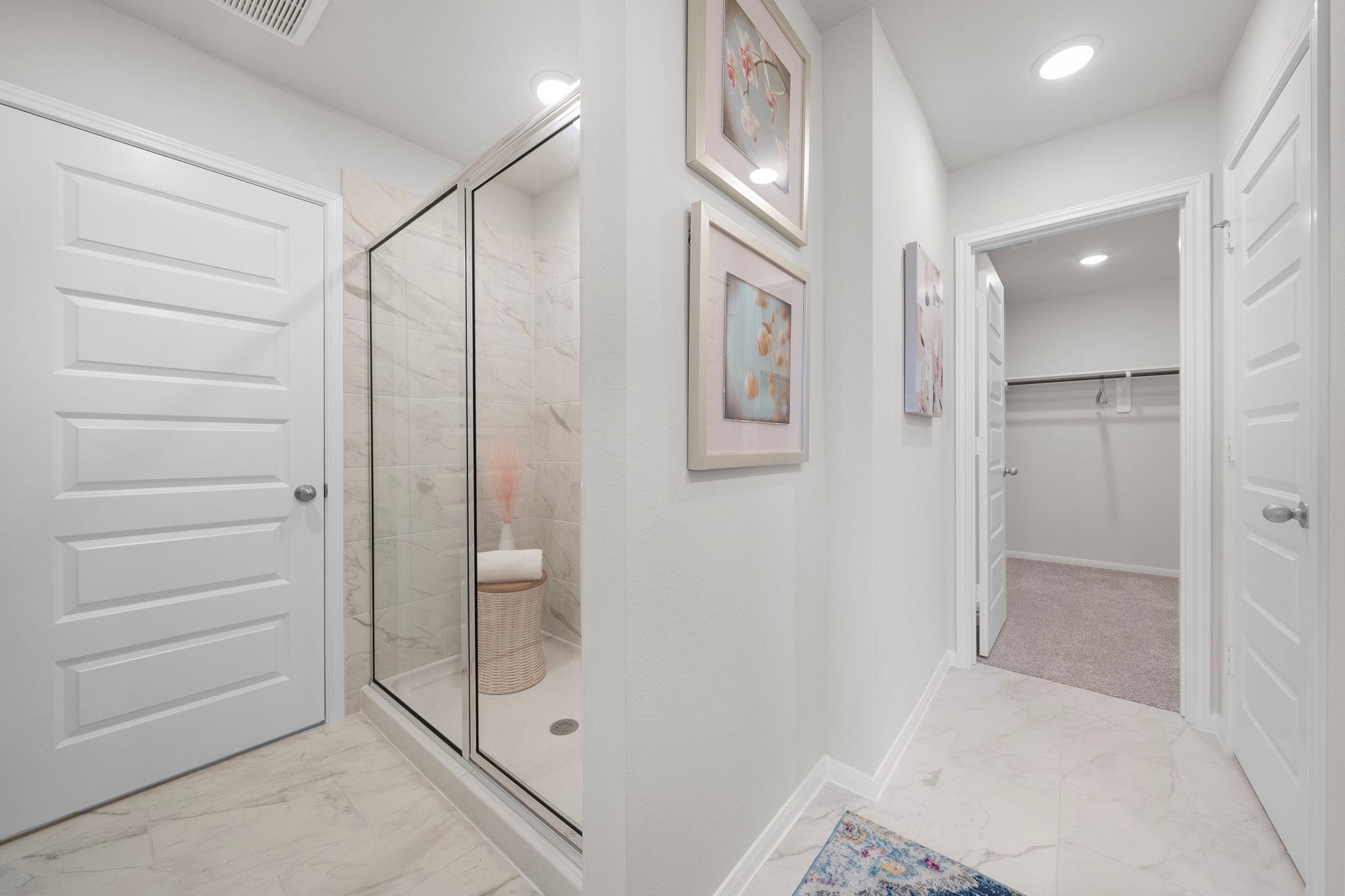 Luxurious primary bathroom with frameless glass shower and adjacent walk-in closet at Hill & Dale Ranch in Splendora Texas