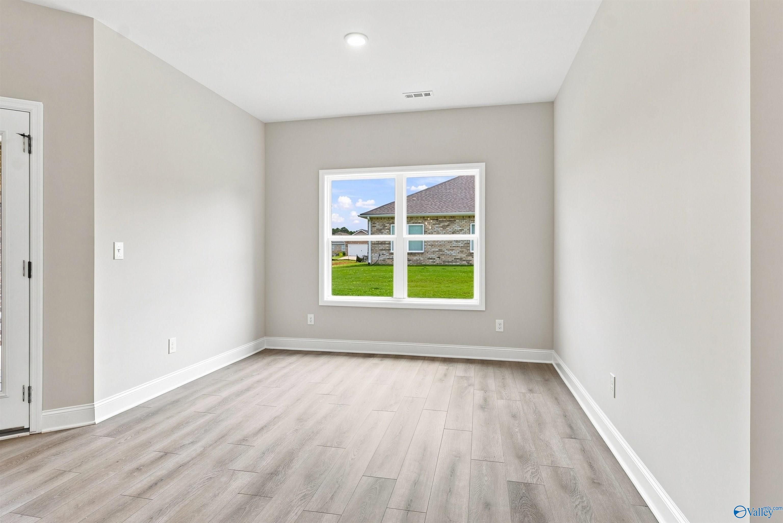 Bright empty room with luxury vinyl plank flooring and white trim in Davidson Homes The Everett B plan, Wood Trail, Toney, Alabama