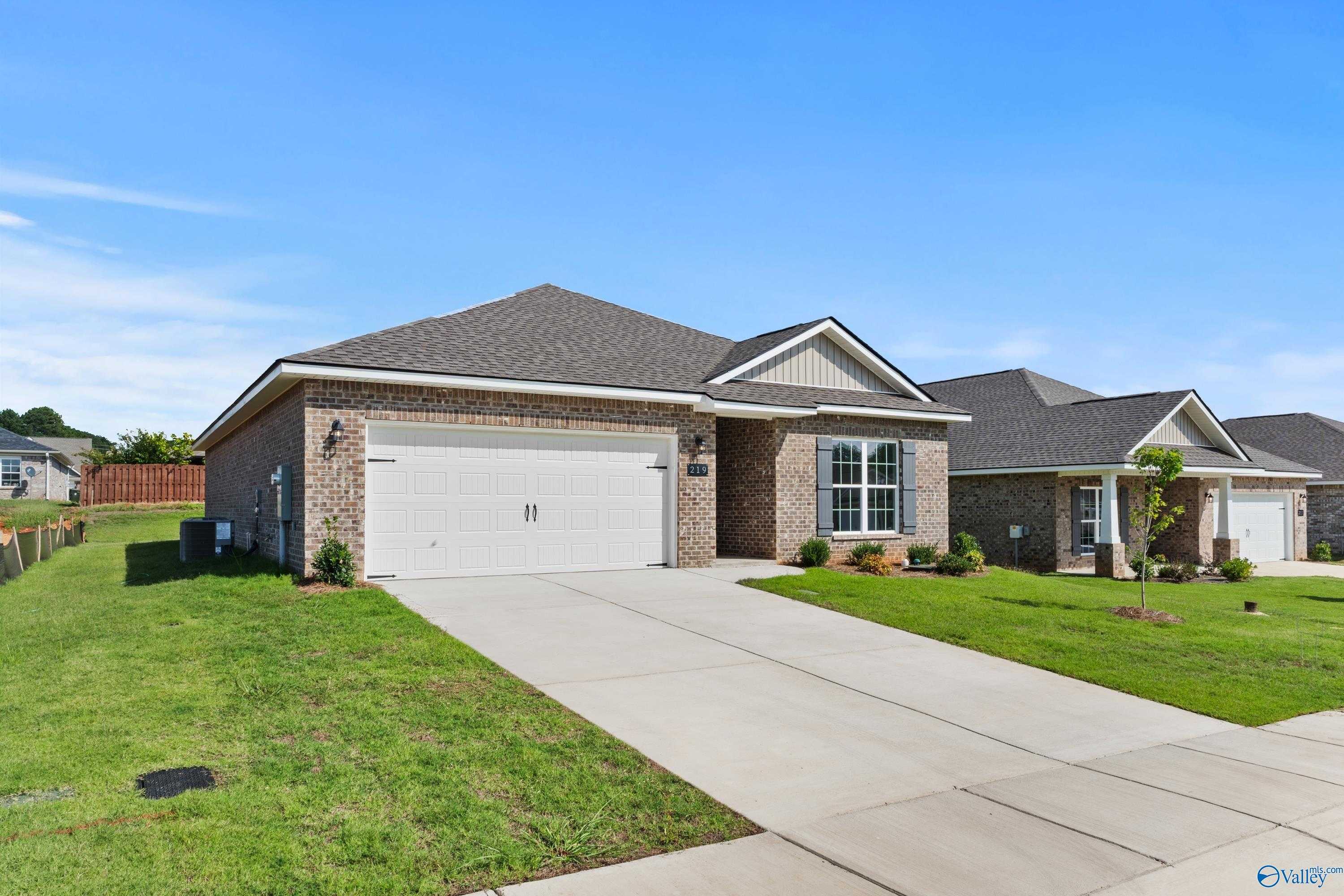 Brick ranch home with 2-car garage, white trim, green lawn, and shrubs in Wood Trail, Toney, Alabama - Davidson Homes Franklin C
