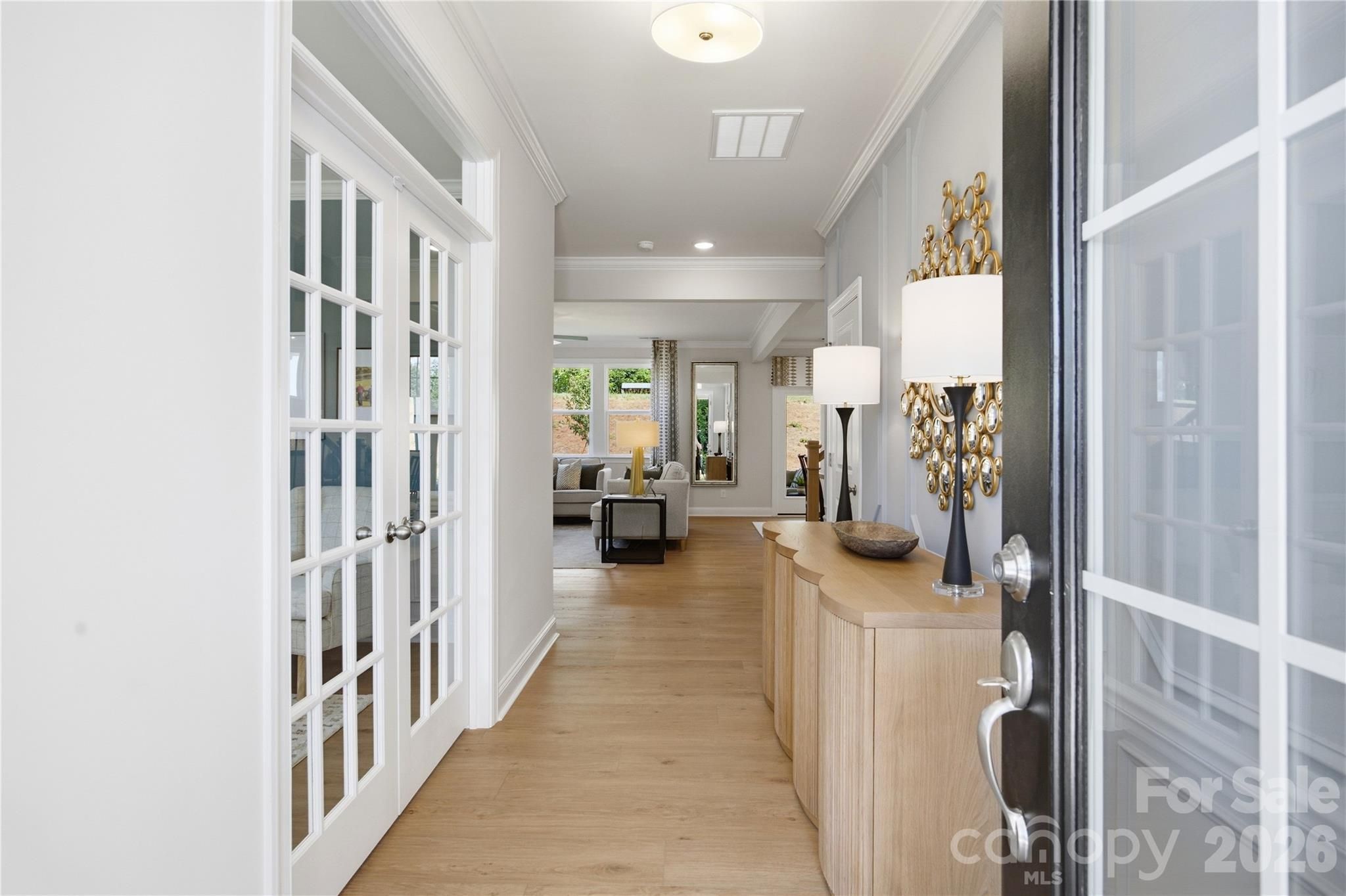 Bright foyer with hardwood floors, glass French doors, and gold accent mirror in Davidson Homes' Hickory C II, Enclave at Belmont, NC