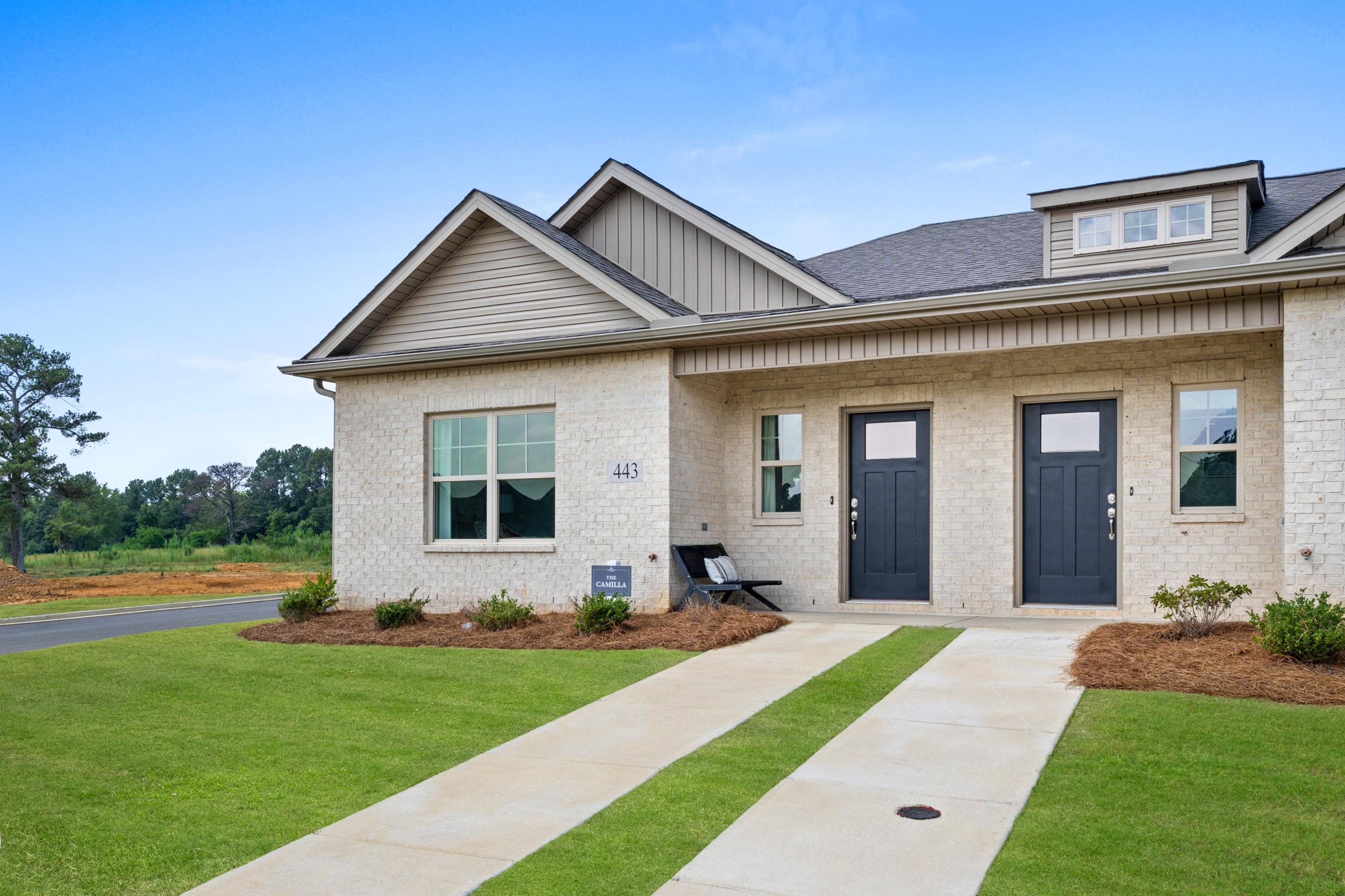 Brick duplex exterior at The Retreat at Cain Park in Hartselle AL with dual black doors, covered porch, and landscaped front yard
