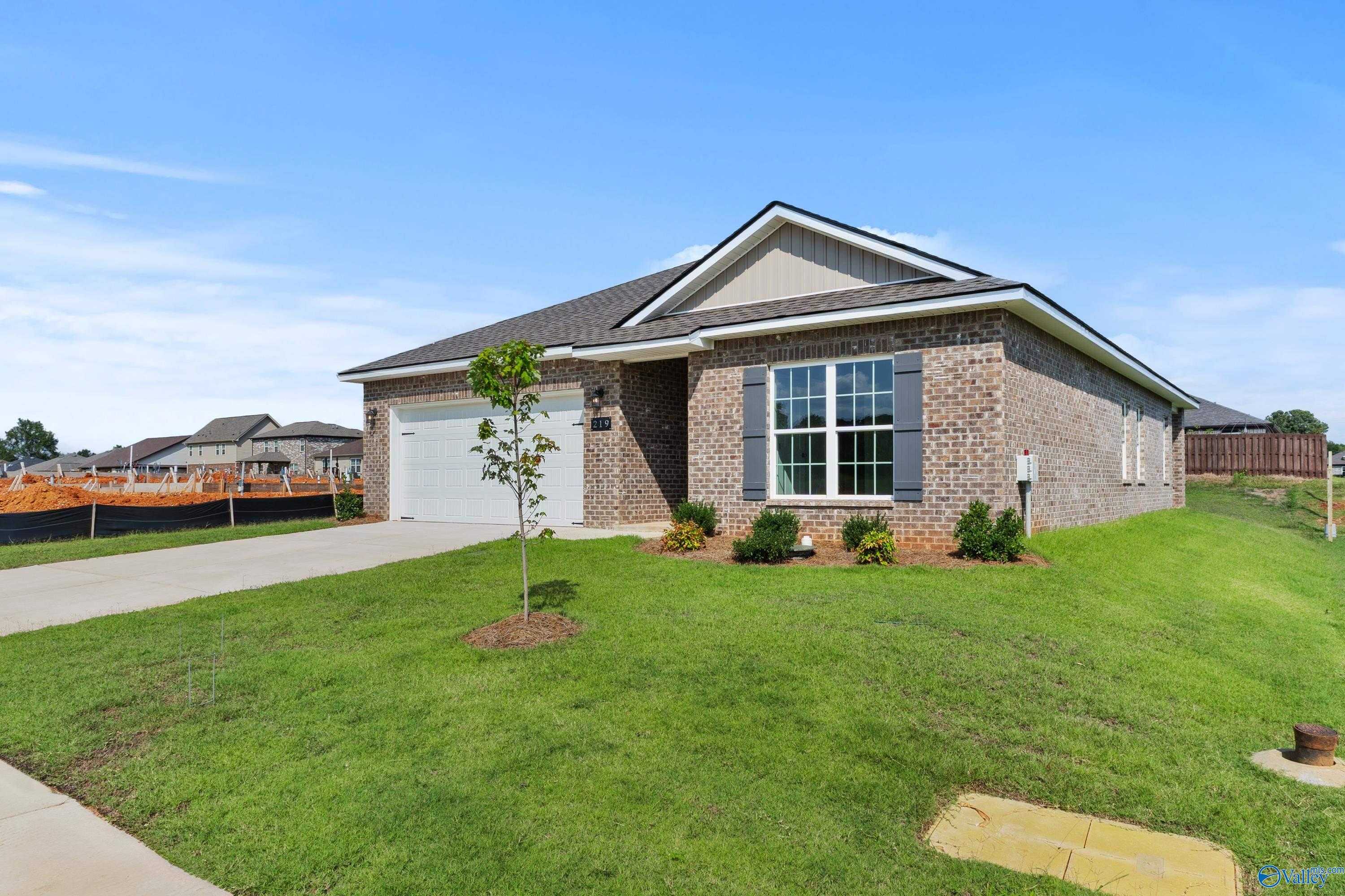 Modern single-story brick home with 2-car garage, driveway, and landscaped lawn in Wood Trail, Toney, Alabama by Davidson Homes