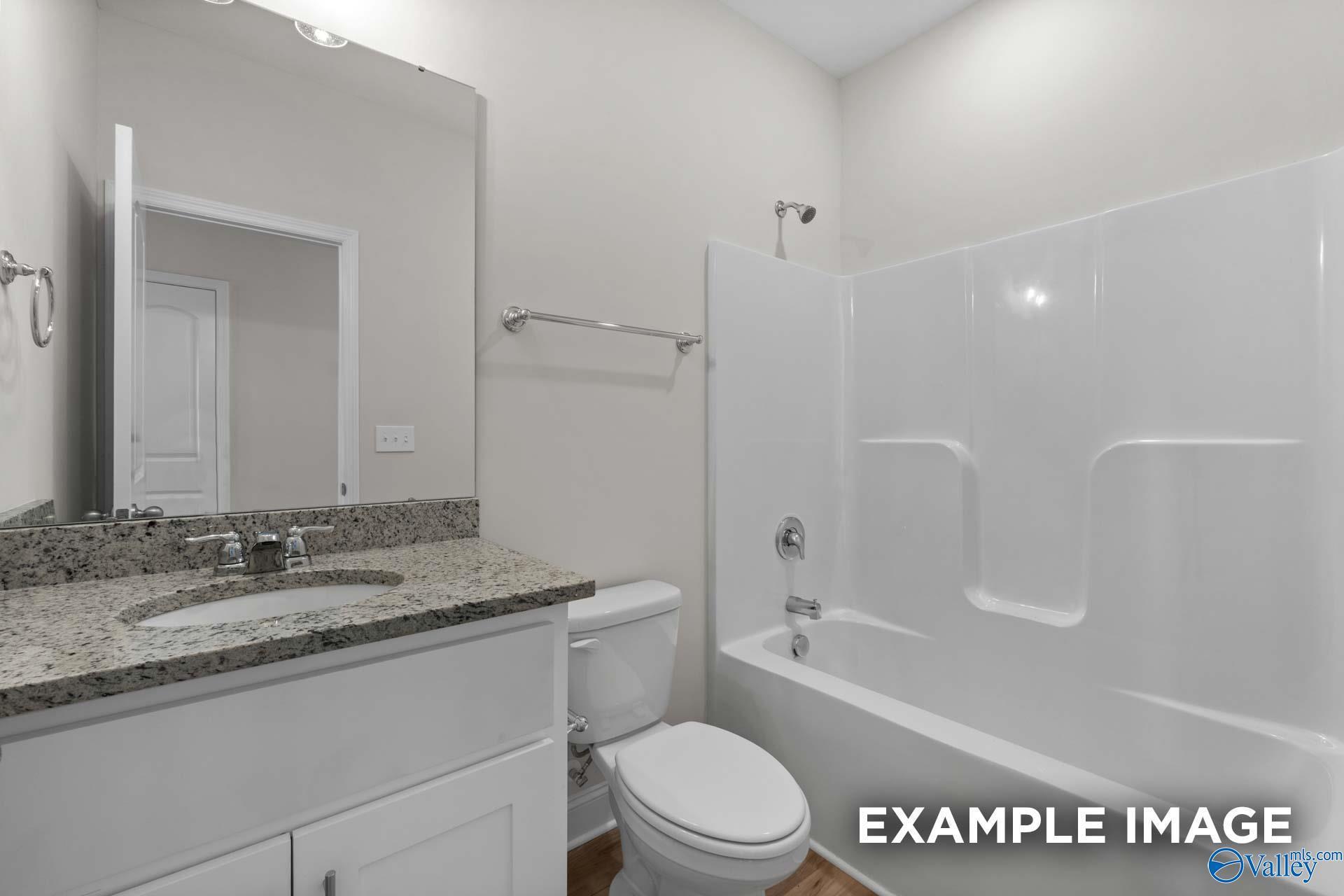 Modern bathroom featuring granite vanity, white bathtub shower combo, and tiled walls in Davidson Homes The Butler, Huntsville, AL