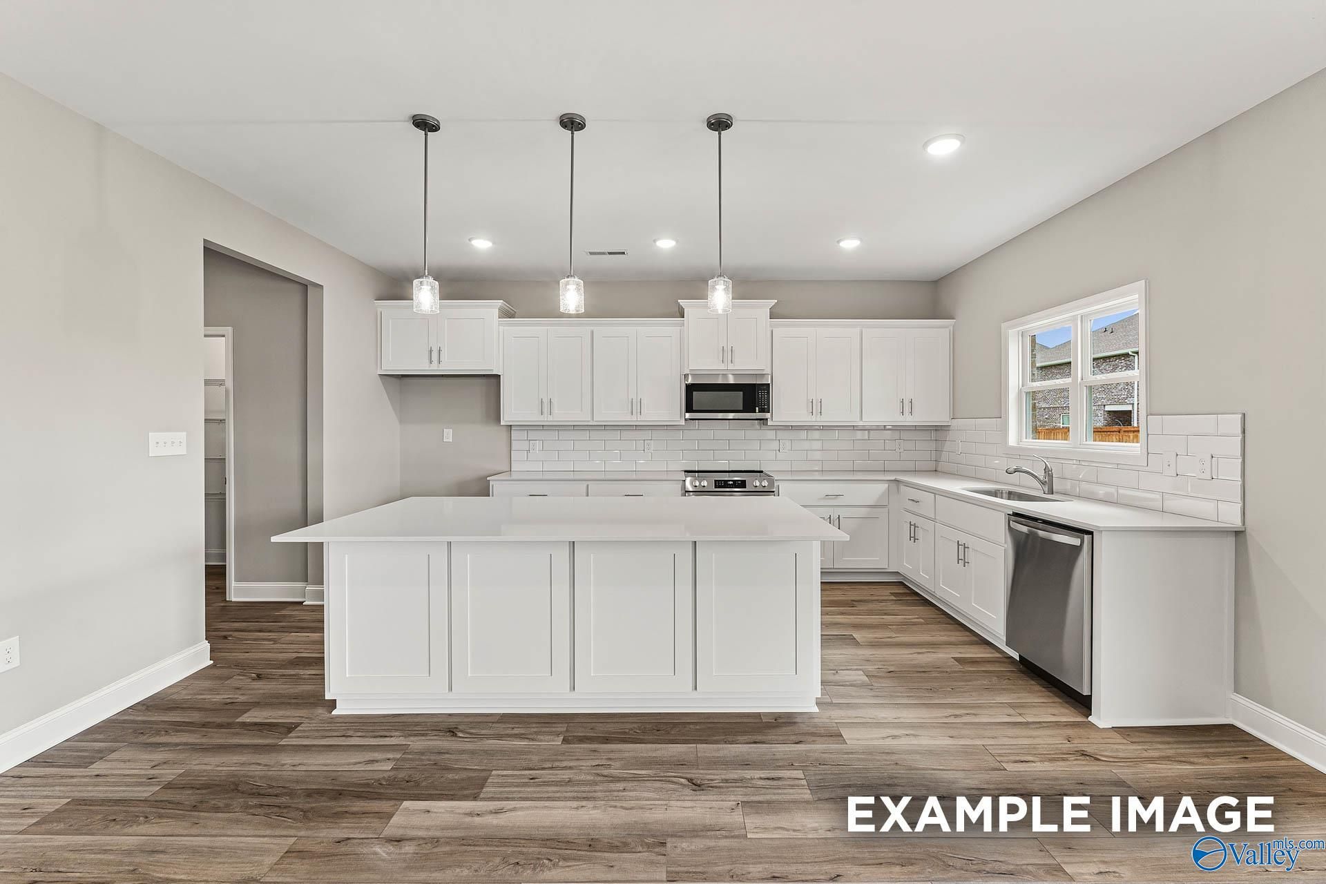 Modern white kitchen with large island, stainless appliances, subway tile backsplash in Davidson Homes Chelsea A, Athens AL