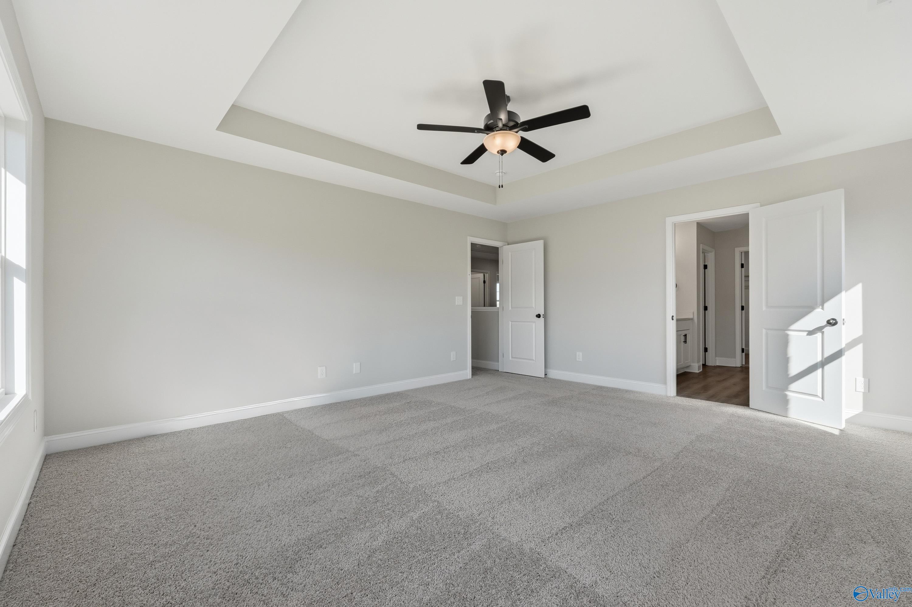 Spacious master bedroom with tray ceiling, ceiling fan, and en-suite bath in Davidson Homes Chelsea C, Harvest, Alabama