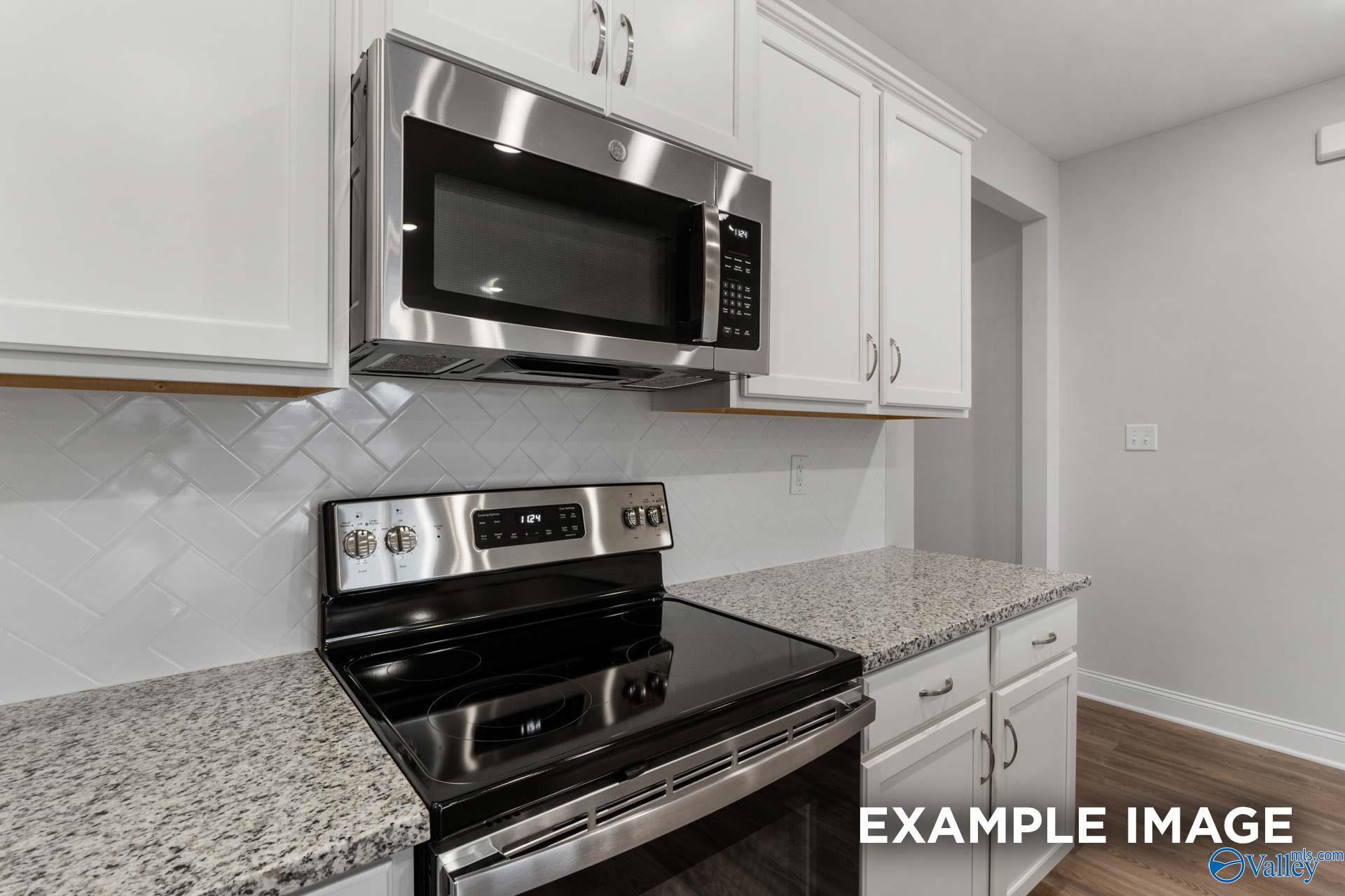 Modern kitchen with white cabinets, stainless steel appliances, granite countertops, and subway tile backsplash in Davidson Homes The Cumberland B, Decatur, Alabama