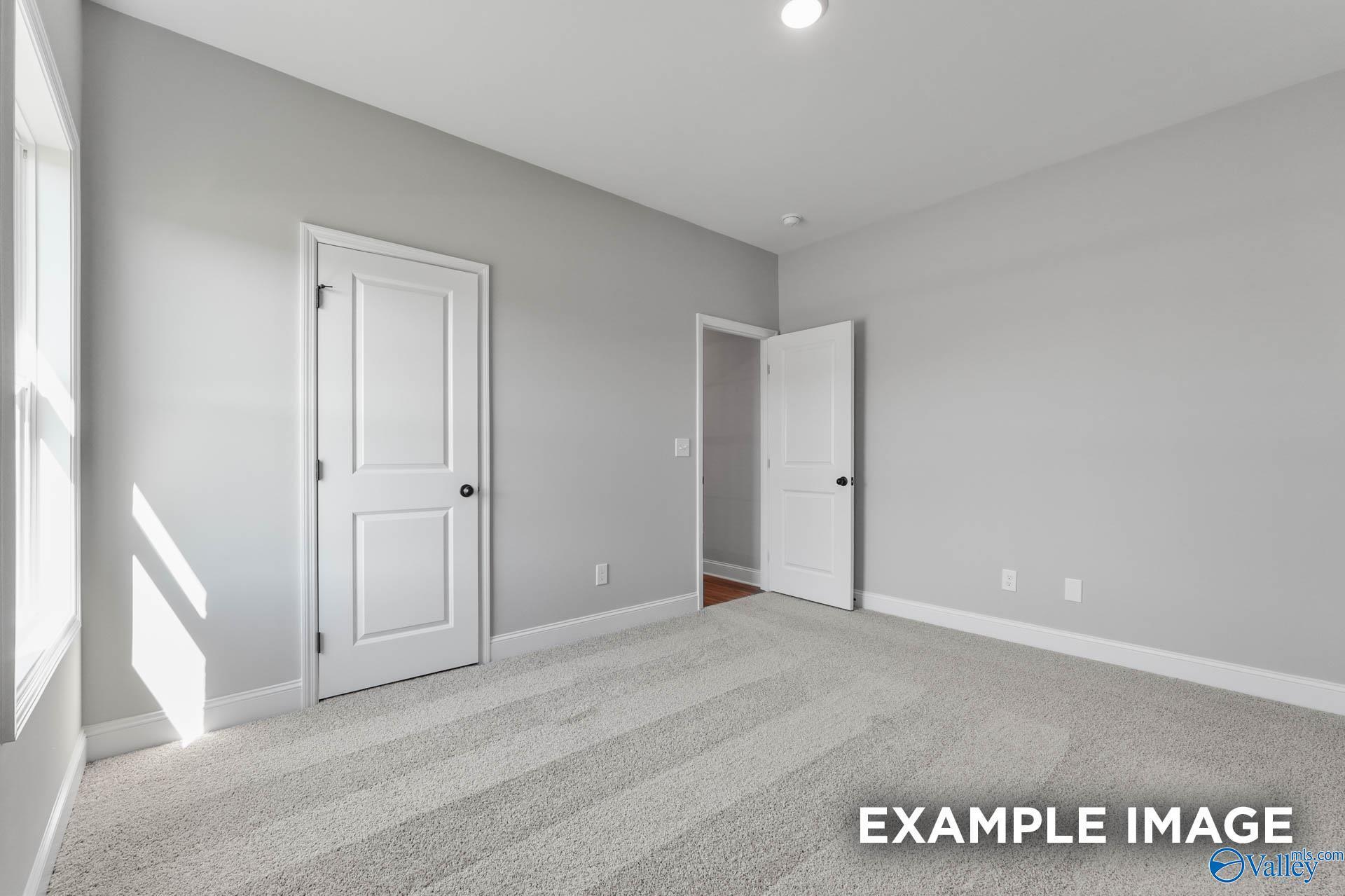 Bright secondary bedroom featuring gray walls, white doors to closet and bath, carpeted floor in Davidson Homes The Daphne C, Athens AL