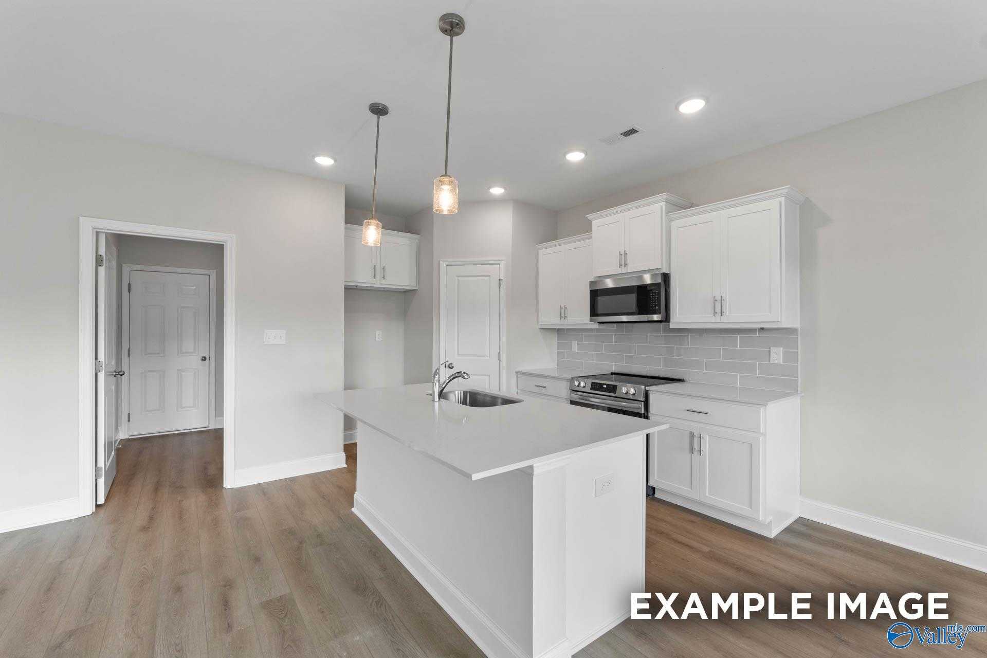 Bright modern kitchen with white shaker cabinets, stainless appliances, quartz island sink, pendant lights in Davidson Homes The Butler, Huntsville AL