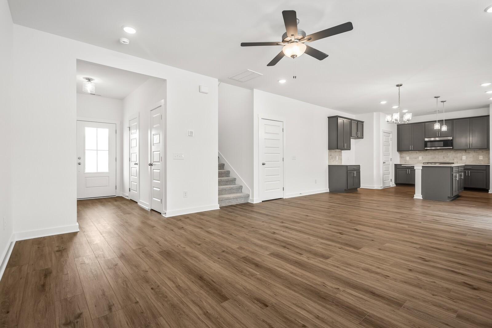 Open-concept kitchen with gray cabinets, island, hardwood floors, and staircase in The Gordon C 3-bedroom home, White House, TN
