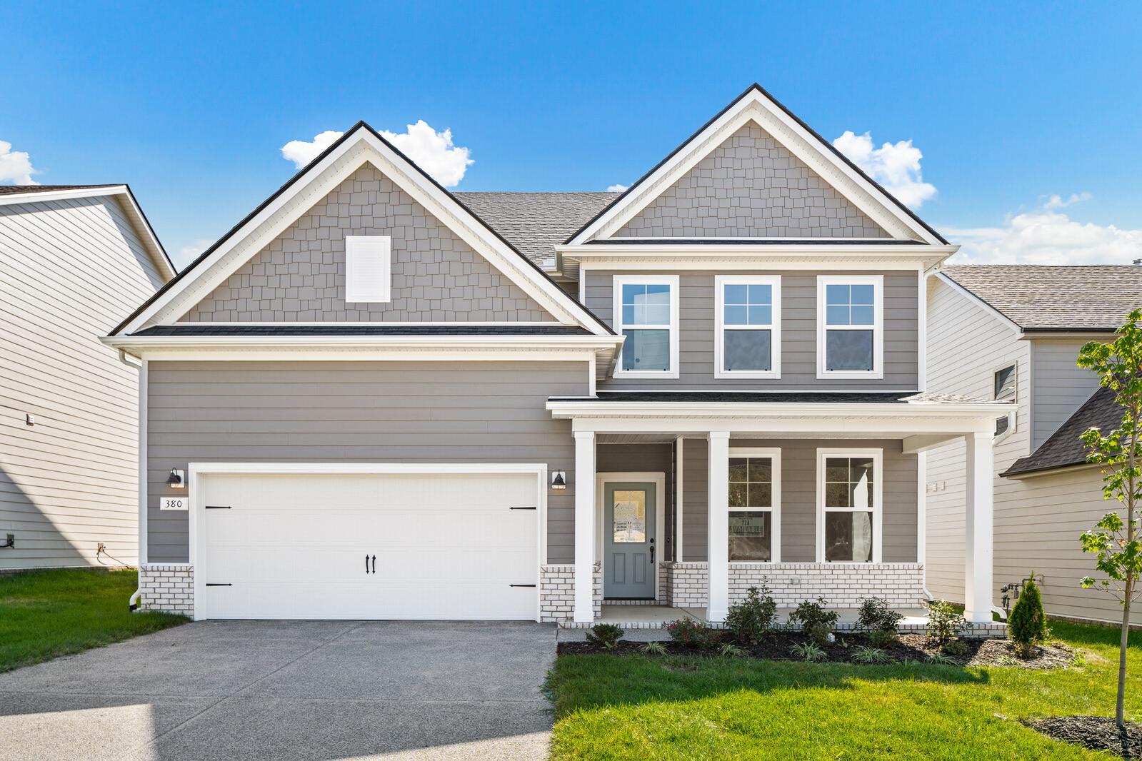 Contemporary two-story home exterior at Woods Crossing in Gallatin Tennessee with gray siding covered porch and garage
