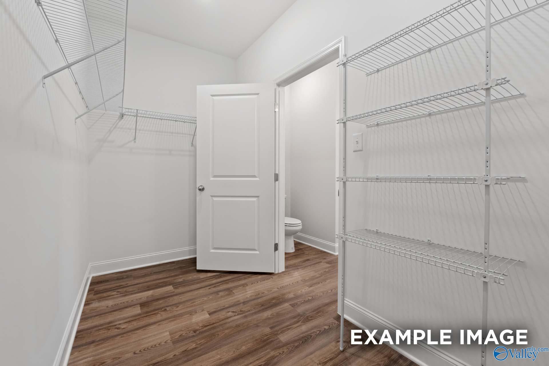 Spacious walk-in closet with wire shelving and adjacent master bath featuring toilet in Davidson Homes The Cumberland, Decatur AL