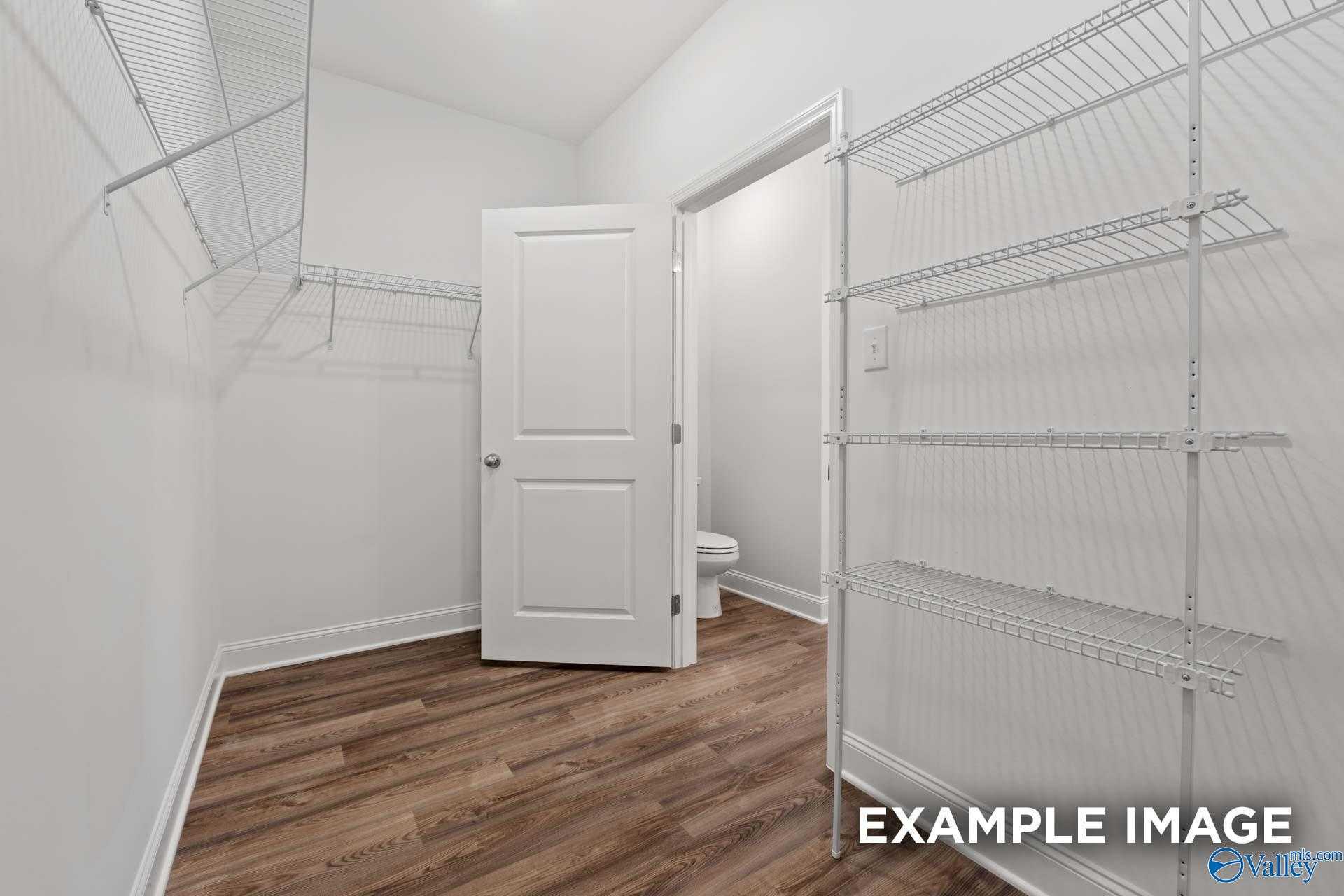Spacious walk-in closet with wire shelving and adjacent master bath featuring toilet in Davidson Homes The Cumberland, Decatur AL