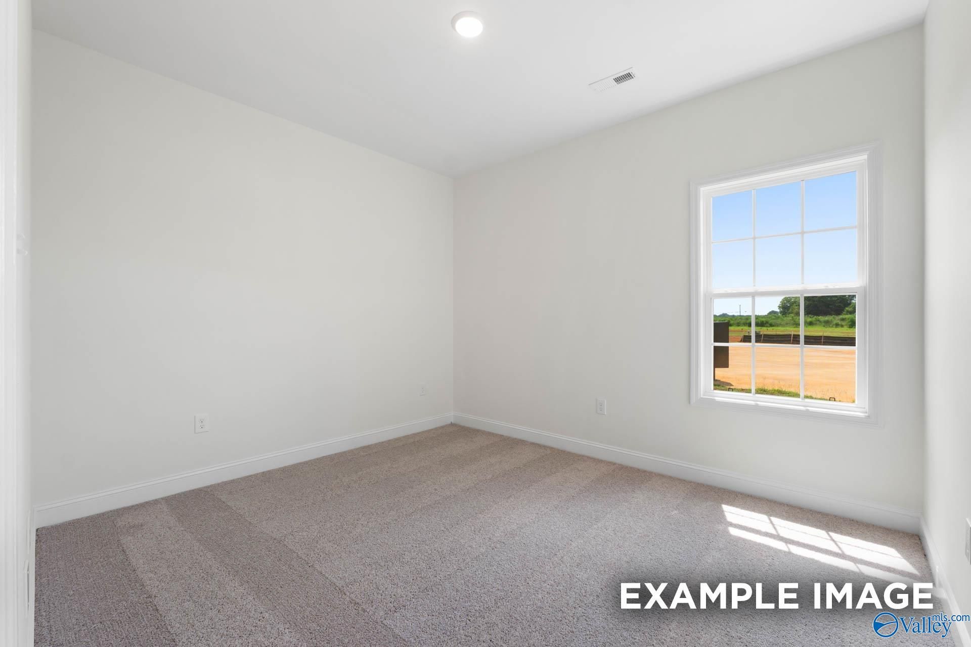 Bright, carpeted bedroom with large window in The Rockford B floor plan at Briercreek in Meridianville, Alabama.