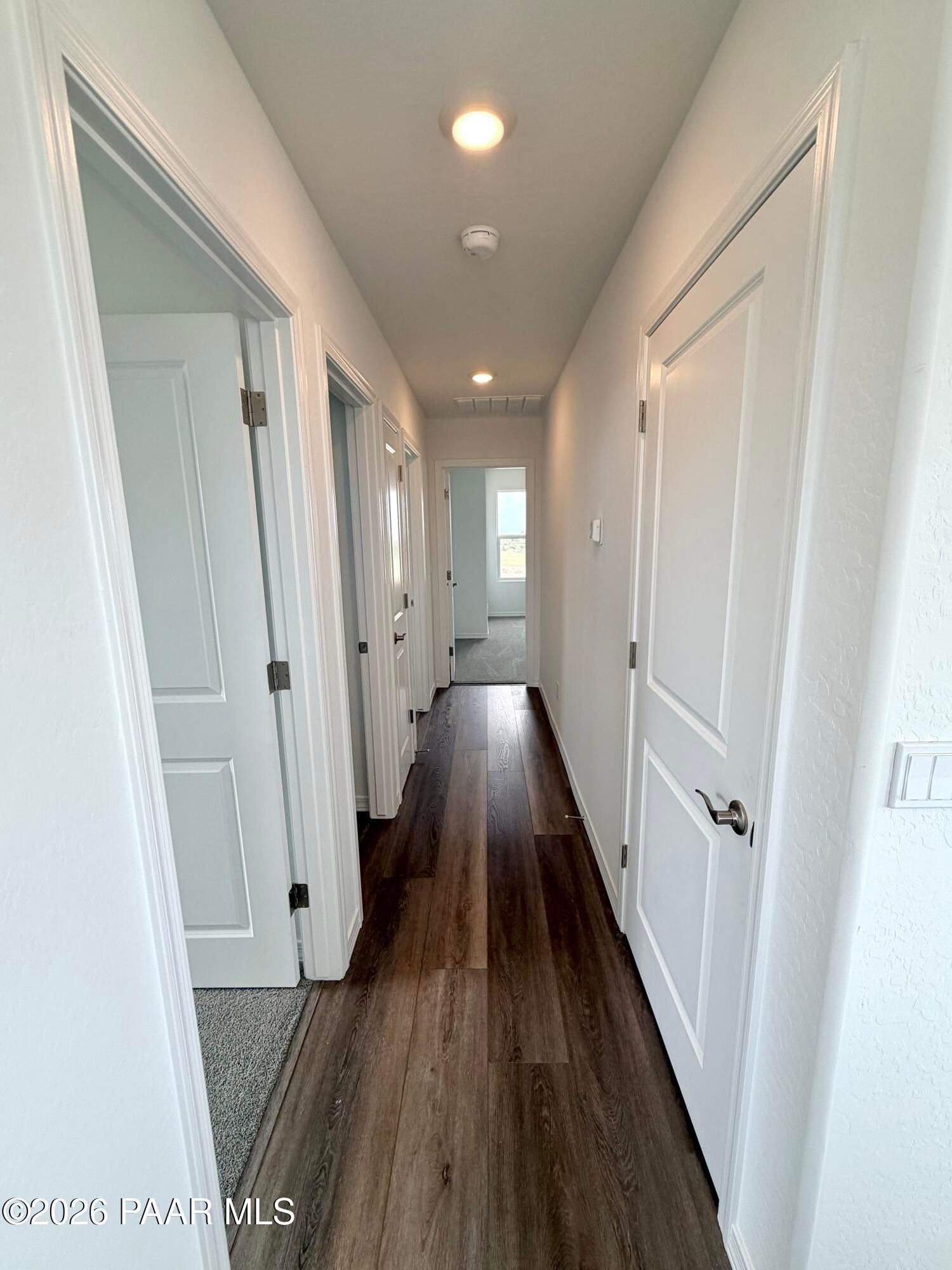 Bright hallway with wood-look flooring connecting rooms in The Raleigh A floor plan at South Ranch, Prescott, Arizona.