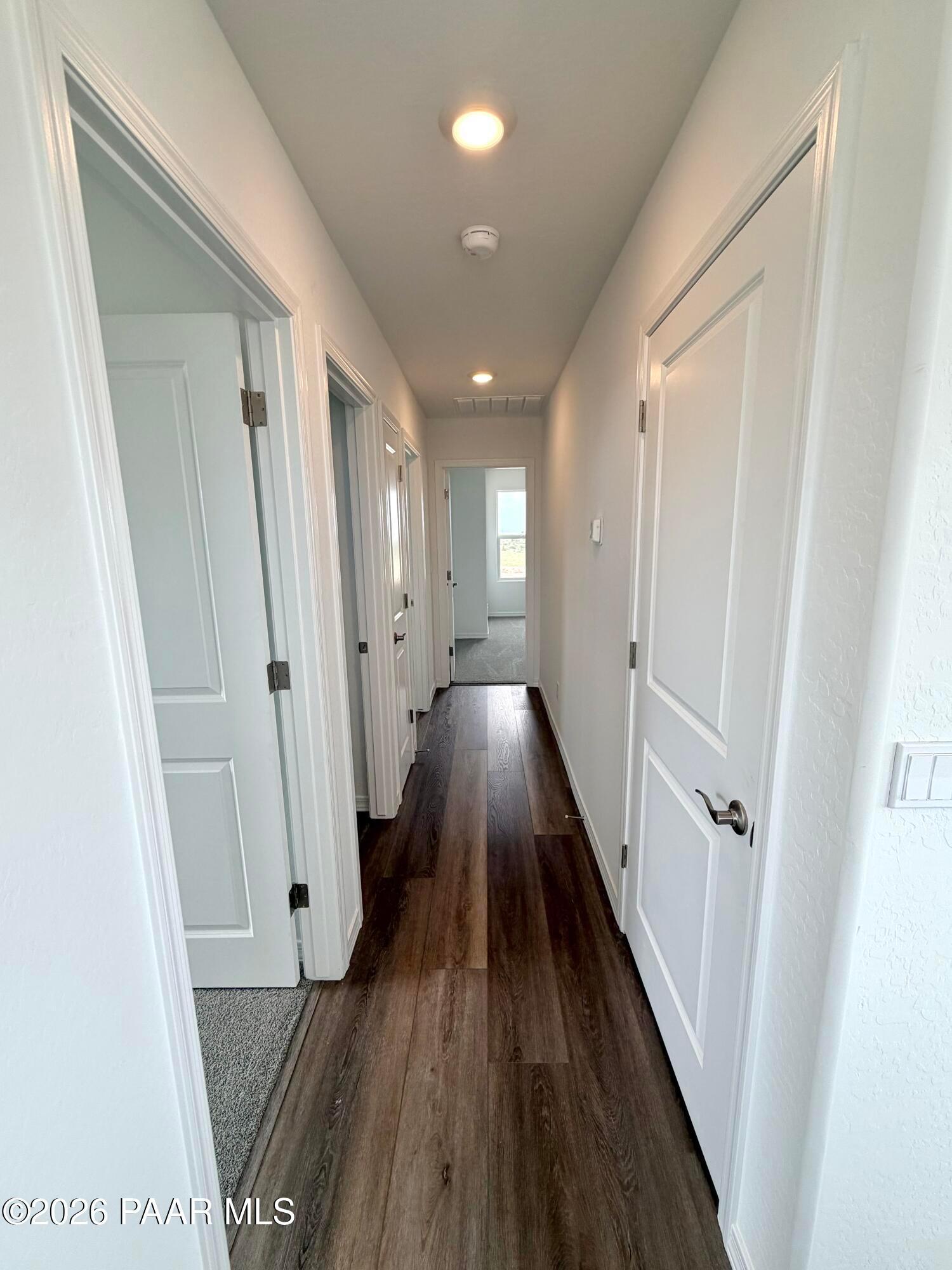 Bright hallway with wood-look flooring connecting rooms in The Raleigh A floor plan at South Ranch, Prescott, Arizona.