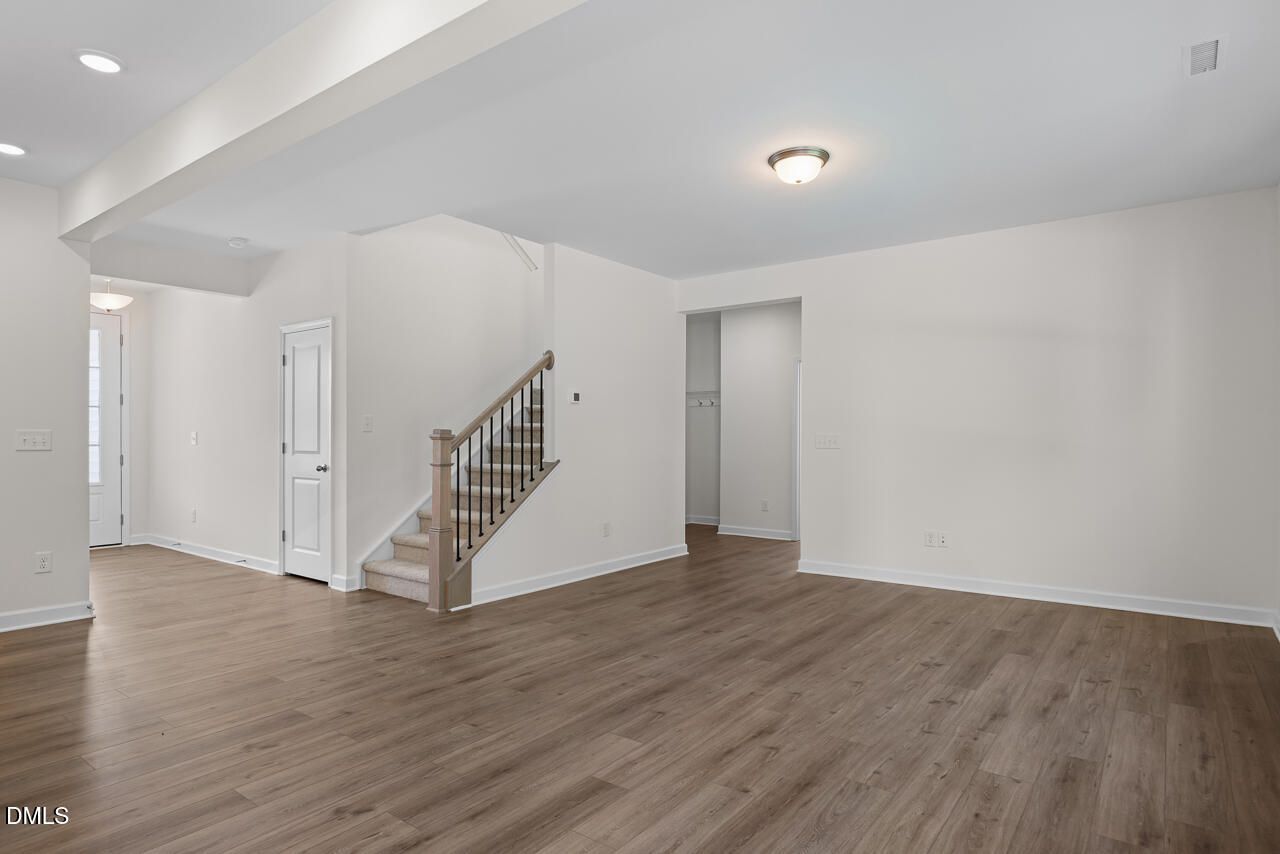 Open-concept living area with luxury vinyl plank flooring and carpeted staircase in Davidson Homes Willow B, Zebulon, NC