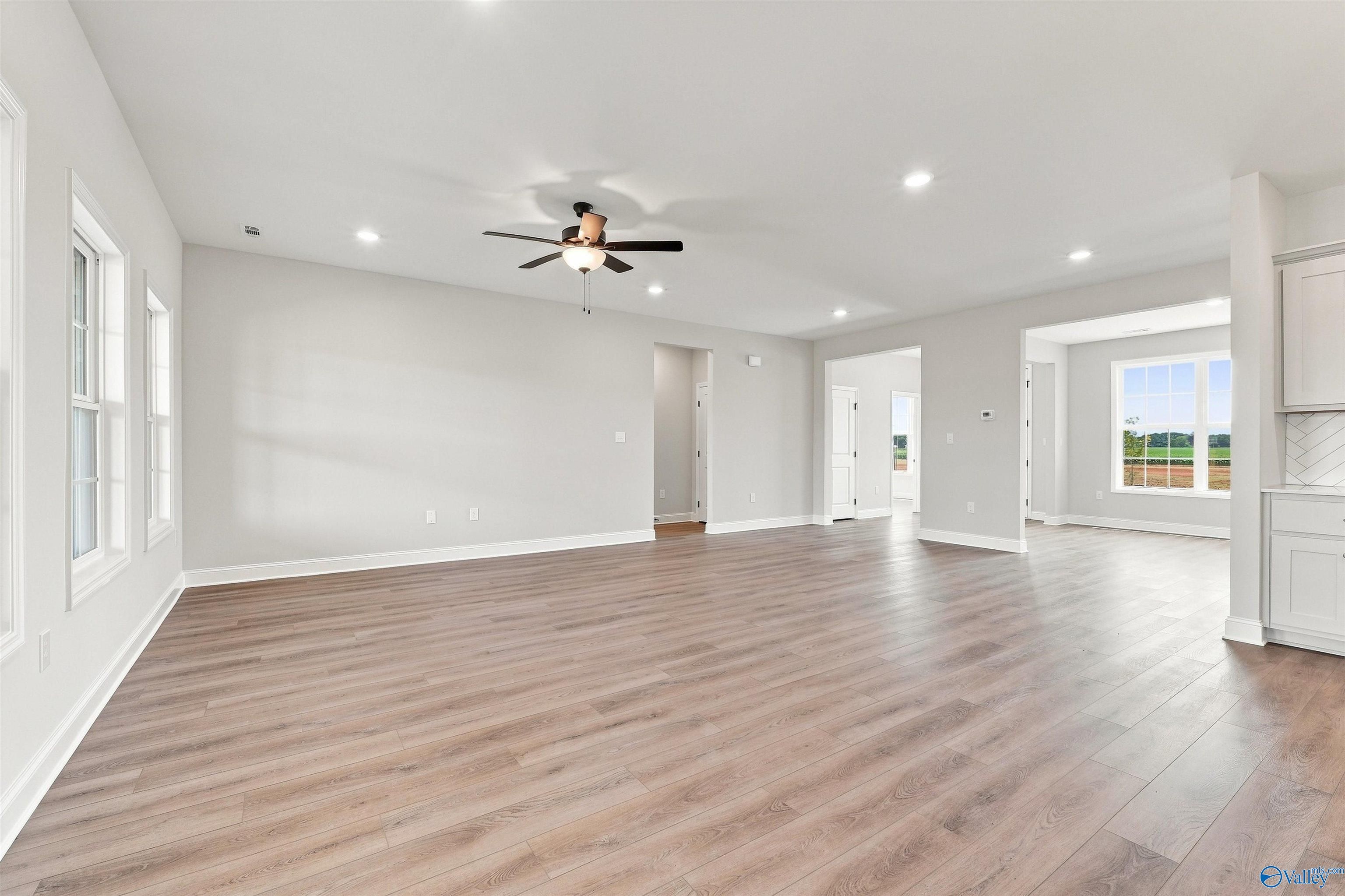 Spacious open-concept living area with wood-style flooring in The Oxford floor plan at Kendall Farms in Toney, Alabama.